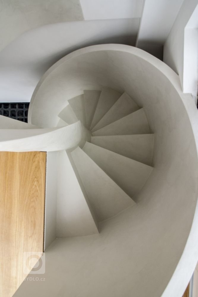 Betonová litá schodiště zpravidla vyžadují opravné úpravy povrchu, které se řeší stěrkou. Stěrka může však být použita na schodišti i k samotnému dekorování, jako například u tohoto bílého schodiště s moniérkou. Stěrkování schodiště vyžaduje precizní práci v hranách a velký smysl pro detail.