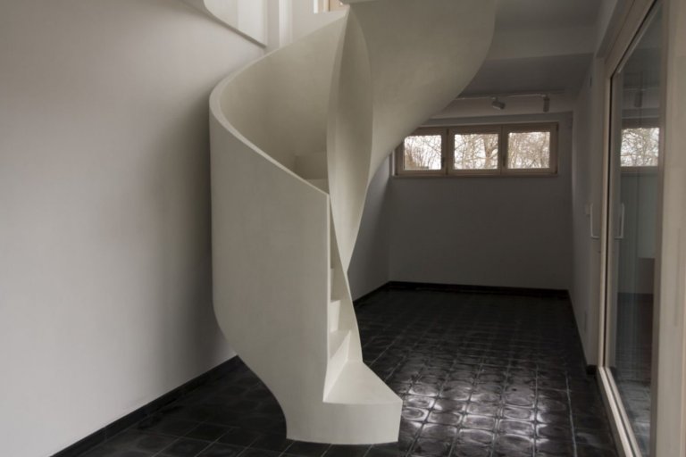 Betonová litá schodiště zpravidla vyžadují opravné úpravy povrchu, které se řeší stěrkou. Stěrka může však být použita na schodišti i k samotnému dekorování, jako například u tohoto bílého schodiště s moniérkou. Stěrkování schodiště vyžaduje precizní práci v hranách a velký smysl pro detail.