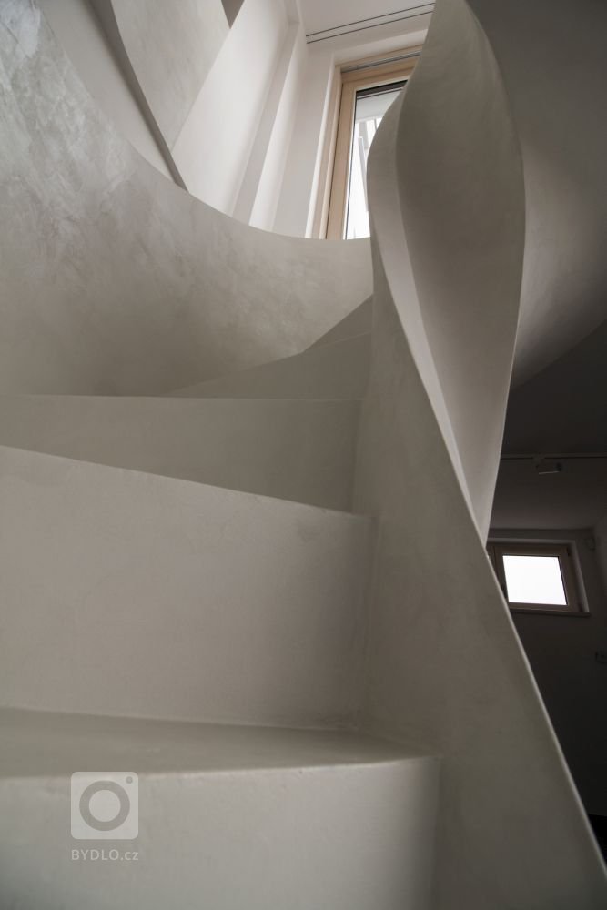 Betonová litá schodiště zpravidla vyžadují opravné úpravy povrchu, které se řeší stěrkou. Stěrka může však být použita na schodišti i k samotnému dekorování, jako například u tohoto bílého schodiště s moniérkou. Stěrkování schodiště vyžaduje precizní práci v hranách a velký smysl pro detail.