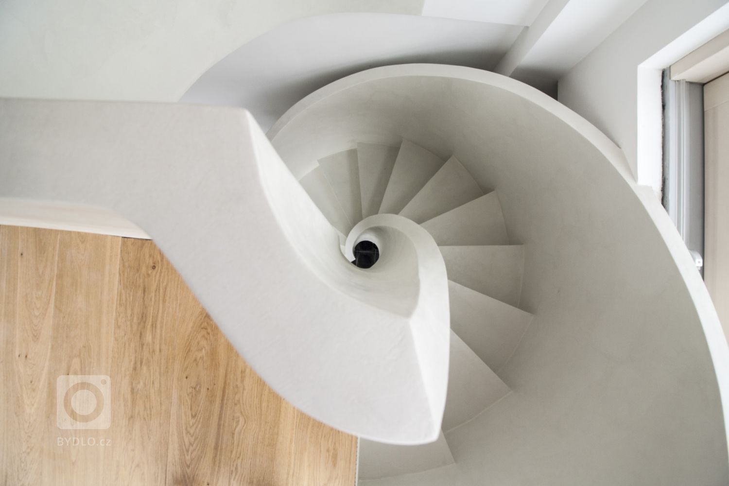 Betonová litá schodiště zpravidla vyžadují opravné úpravy povrchu, které se řeší stěrkou. Stěrka může však být použita na schodišti i k samotnému dekorování, jako například u tohoto bílého schodiště s moniérkou. Stěrkování schodiště vyžaduje precizní práci v hranách a velký smysl pro detail.