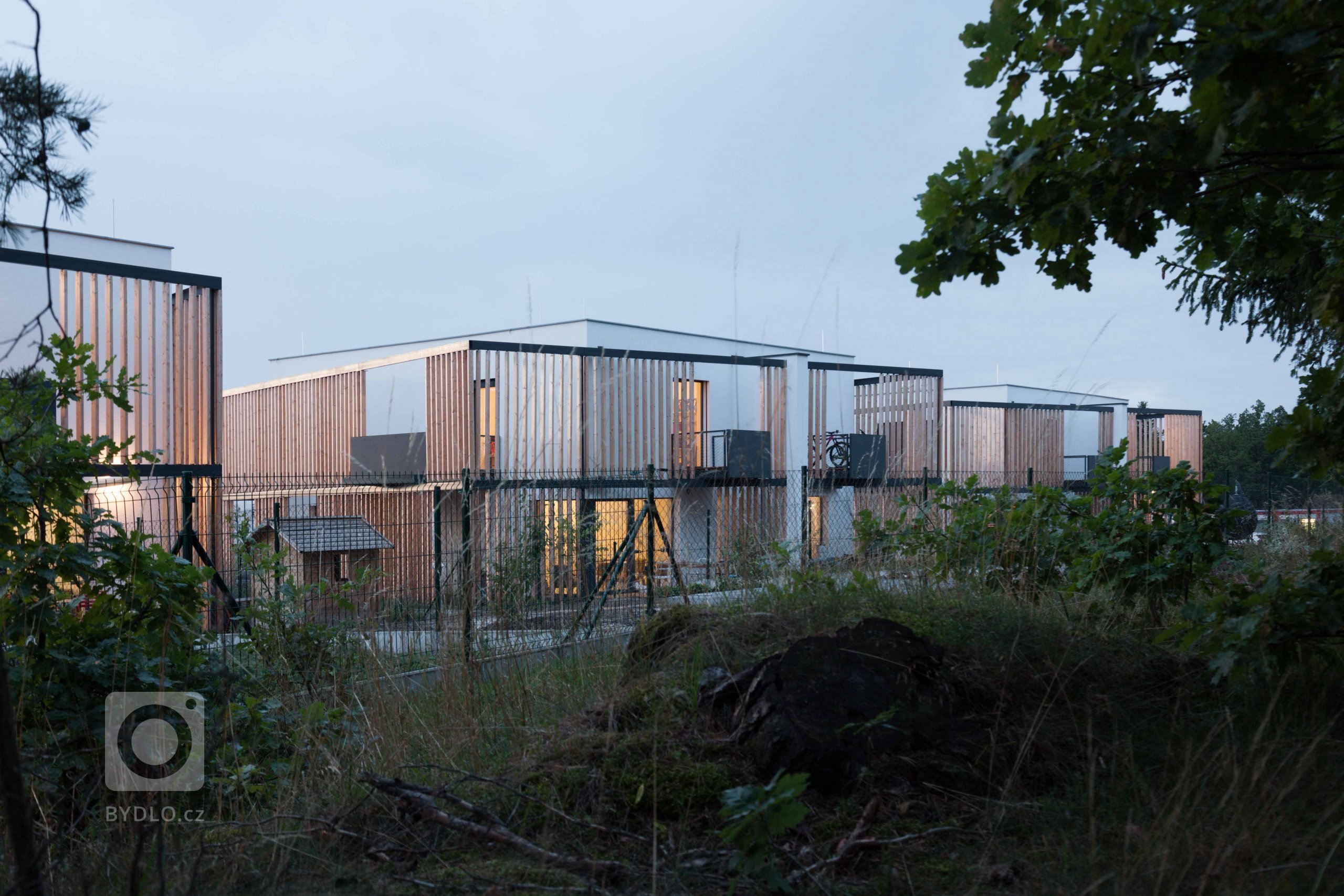 Koncept
Jednoduché krychle doplněné předsazenou dřevěnou konstrukcí. Semknutá, účelná dispozice využívající výhledů do krajiny. To je developerský projekt Za…