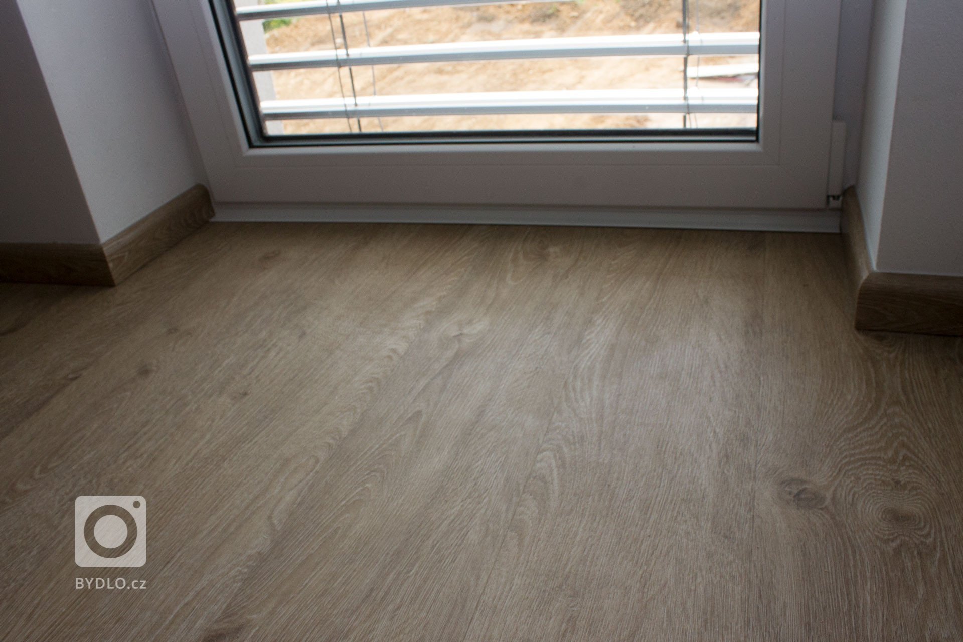 Ukončení podlahy bílou lištou u bílých balkónových dveří