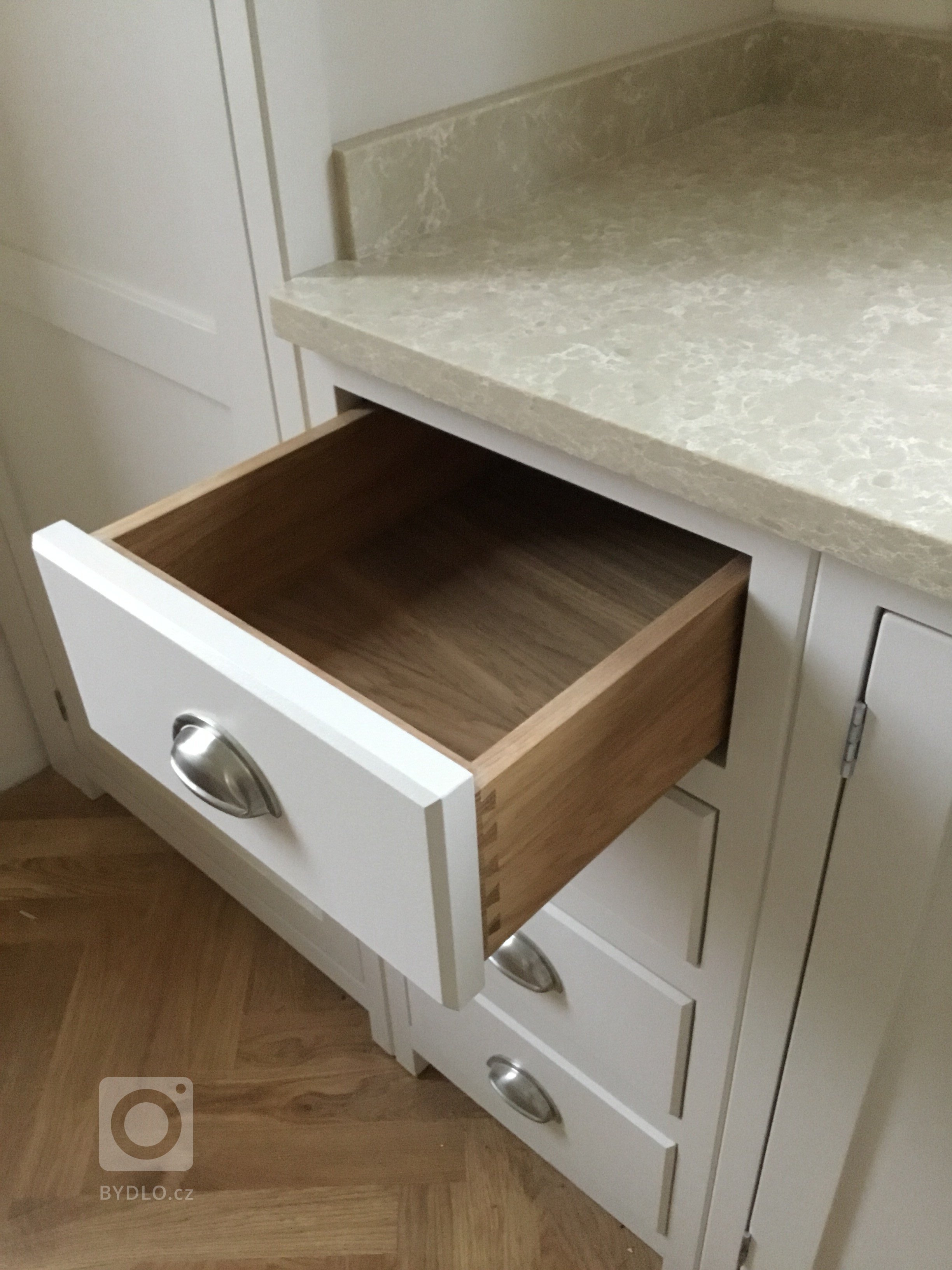 Šuplíky vyrobené z dubového dřeva, s rybinovým čepem a na BLUM soft close pojezdech.  Úchyty dovezené z Anglie.