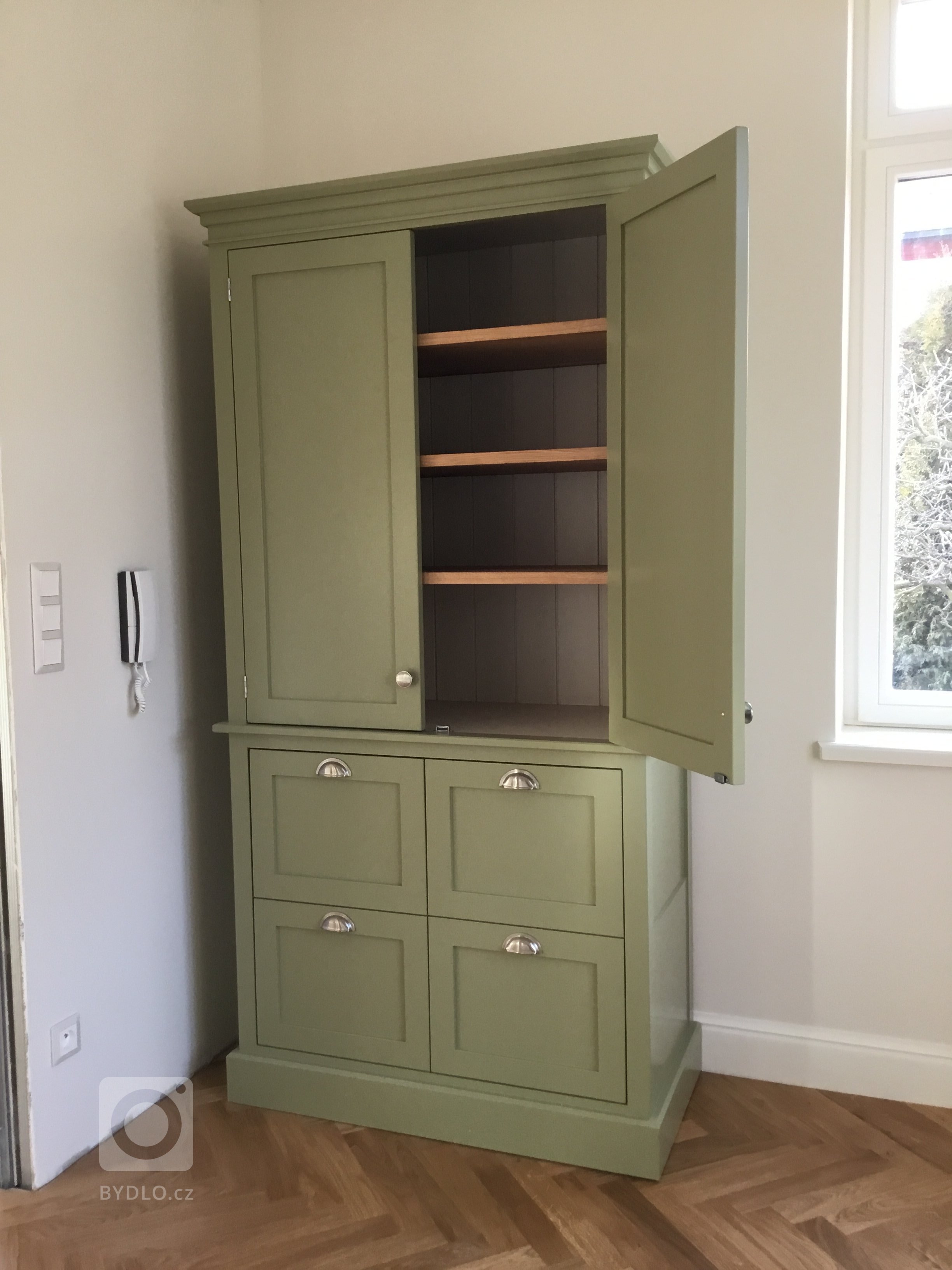 Kredenc v tmavší olivové zelené. Uvnitř výškově nastavitelné police z dubového dřeva.