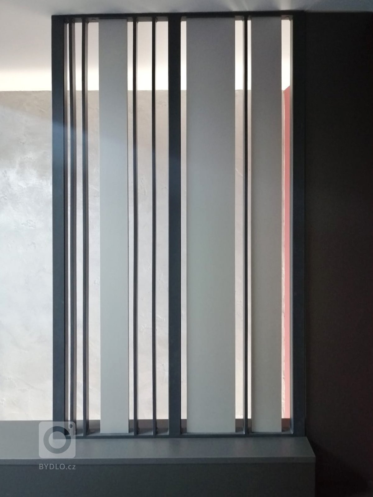 Dělicí stěna vymezující prostor ke schodišťové šachtě v kombinaci kovu a stříbrného LTD. Stejný prvek byl použit i do podkroví. 