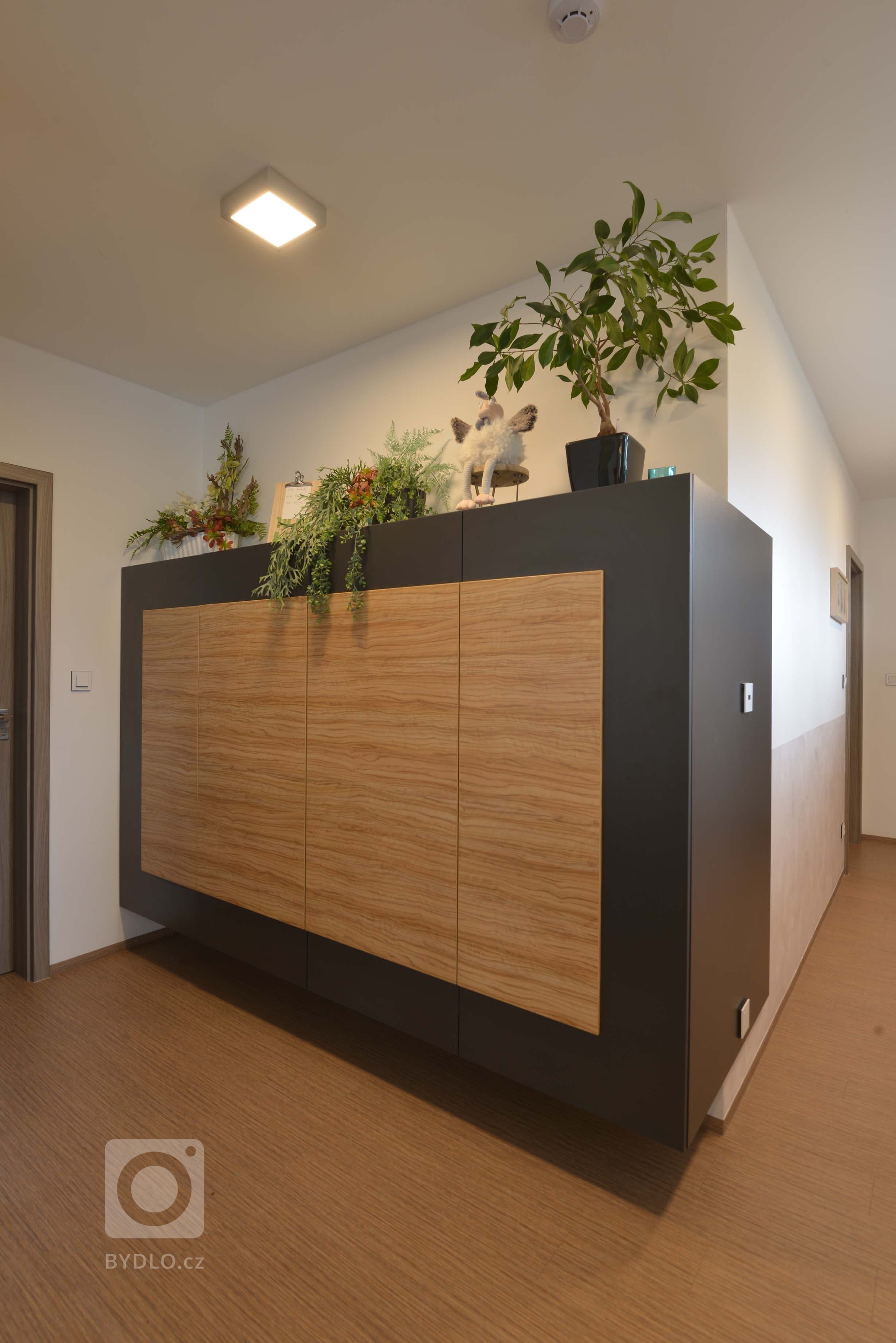 Přechod do další části bytu zakončuje zavěšená komoda v kombinaci antracitové a olivy,