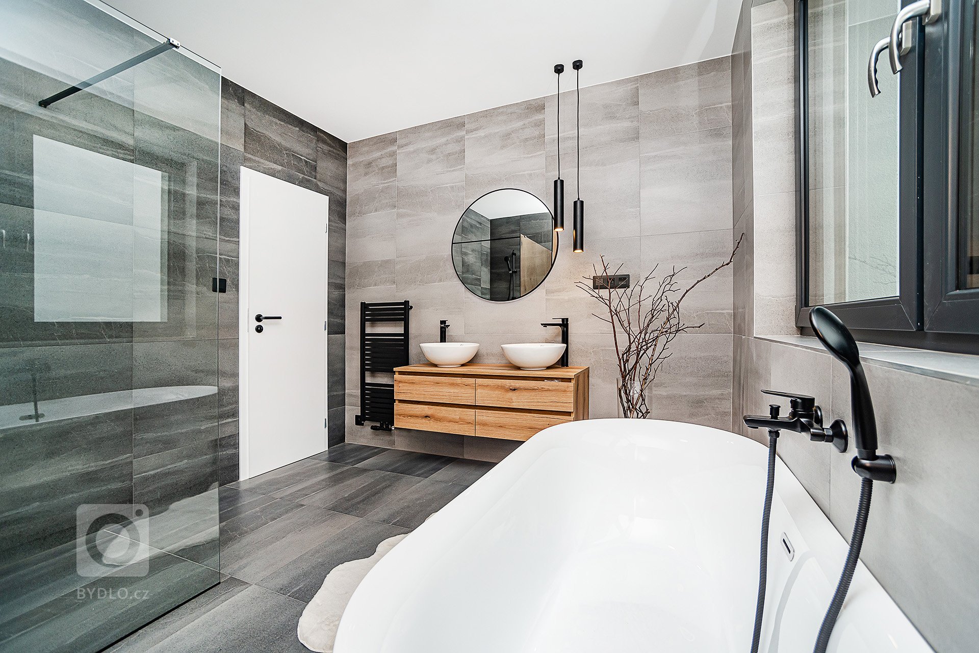Interiér rodinného domu byl navržen v kombinaci olejovaného dubu, laminátu v odstínu taupe,&nbsp;černého lakovaného kovu a šedých odstínech velkoformátové…