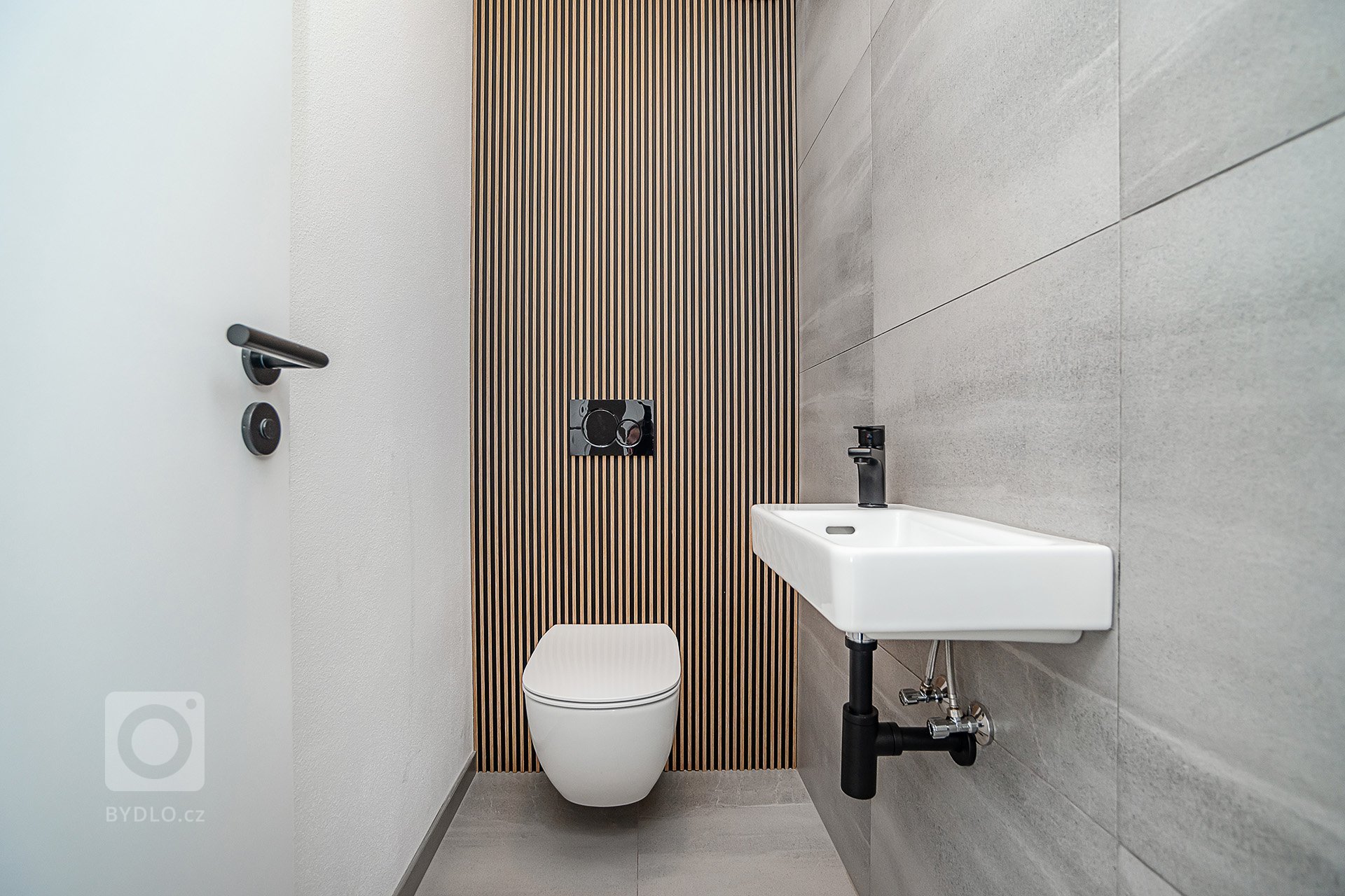 Interiér rodinného domu byl navržen v kombinaci olejovaného dubu, laminátu v odstínu taupe,&nbsp;černého lakovaného kovu a šedých odstínech velkoformátové…