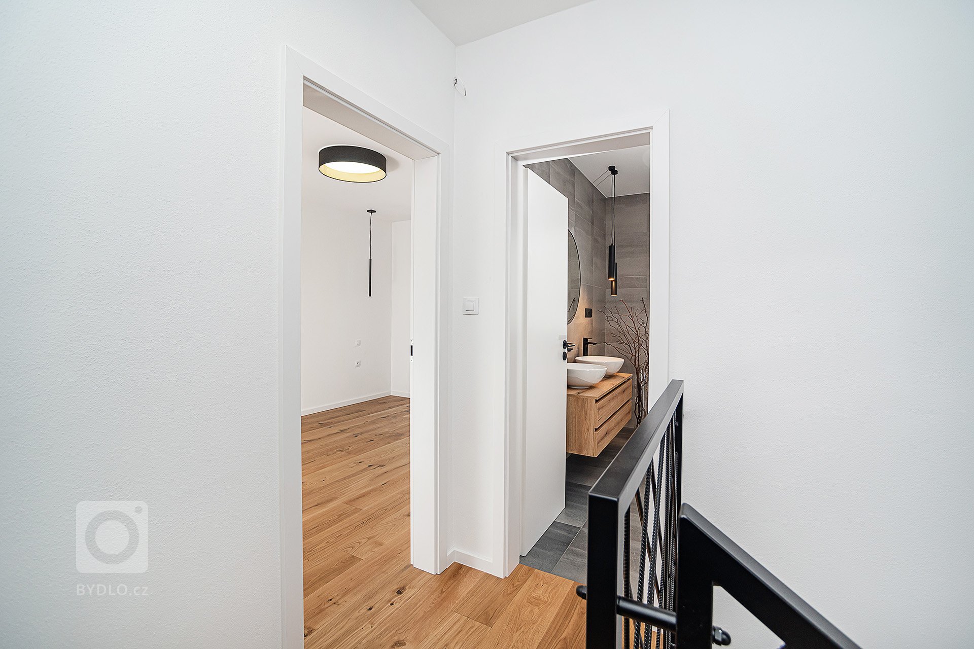 Interiér rodinného domu byl navržen v kombinaci olejovaného dubu, laminátu v odstínu taupe,&nbsp;černého lakovaného kovu a šedých odstínech velkoformátové…