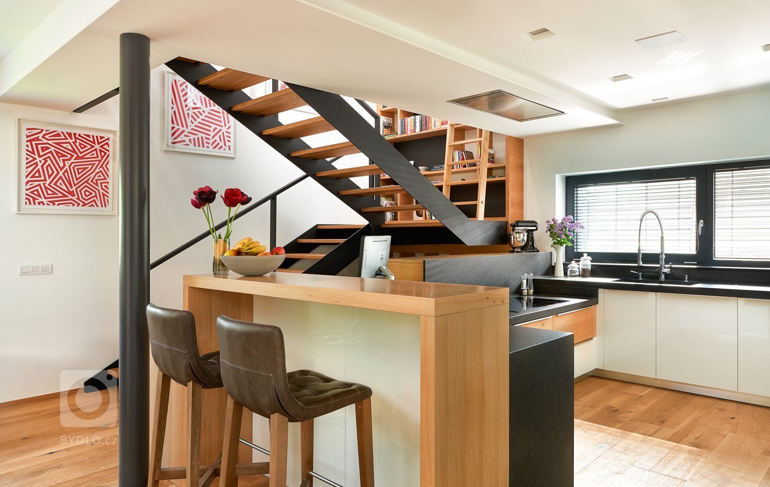 Interiér, kde se prolíná dýha dub rustikální přírodní spolu s bílým lakem ve vysokém lesku. Kuchyně získala v tomto prostorném domě místo při schodišti, které…