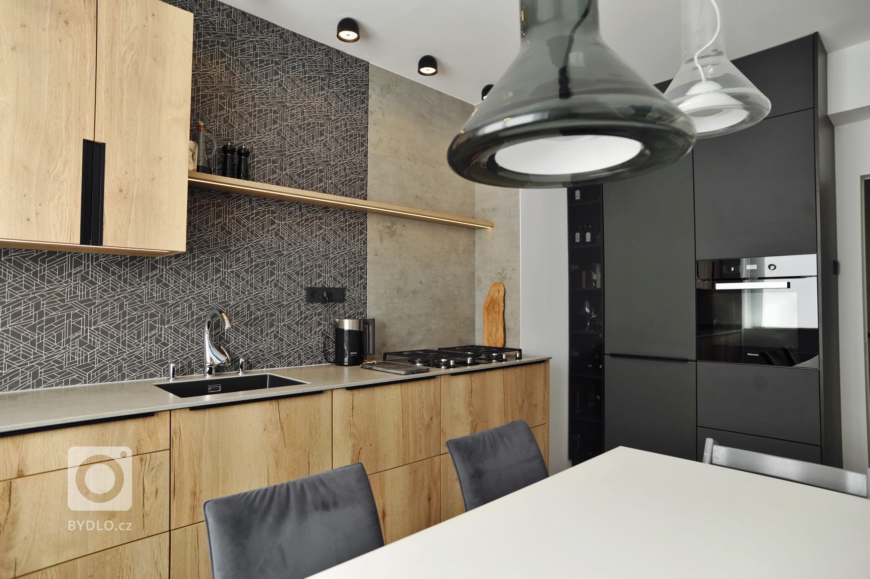 Realizace kuchyně ve skandinávském stylu. Schüller Cremona &ndash; imitace dub v kombinaci s matným sklem. Pracovní deska z keramiky, obklad z řezané mozaiky v…