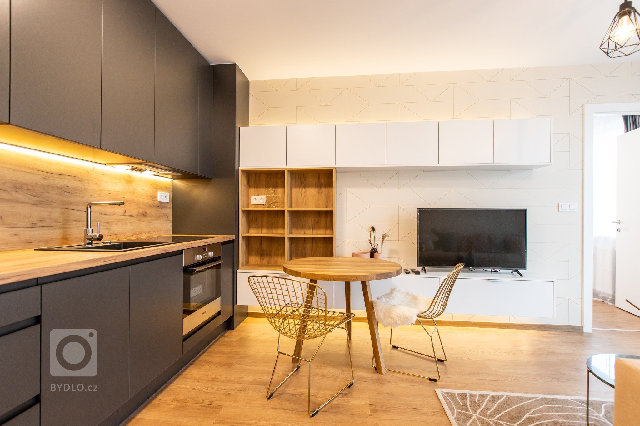 Krásna realizácia, ktorá dokonale prepája antracitovú kuchyňu s bielou obývacou zostavou.
