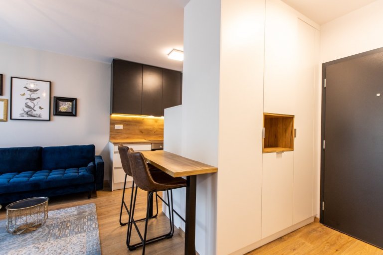 Krásne minimalisticky zariadený byt v Urban Residence, ktorého dominantou je modrá rohová sedačka. Kuchynská linka je krásne ladená v tónoch ceého bytu, aby…