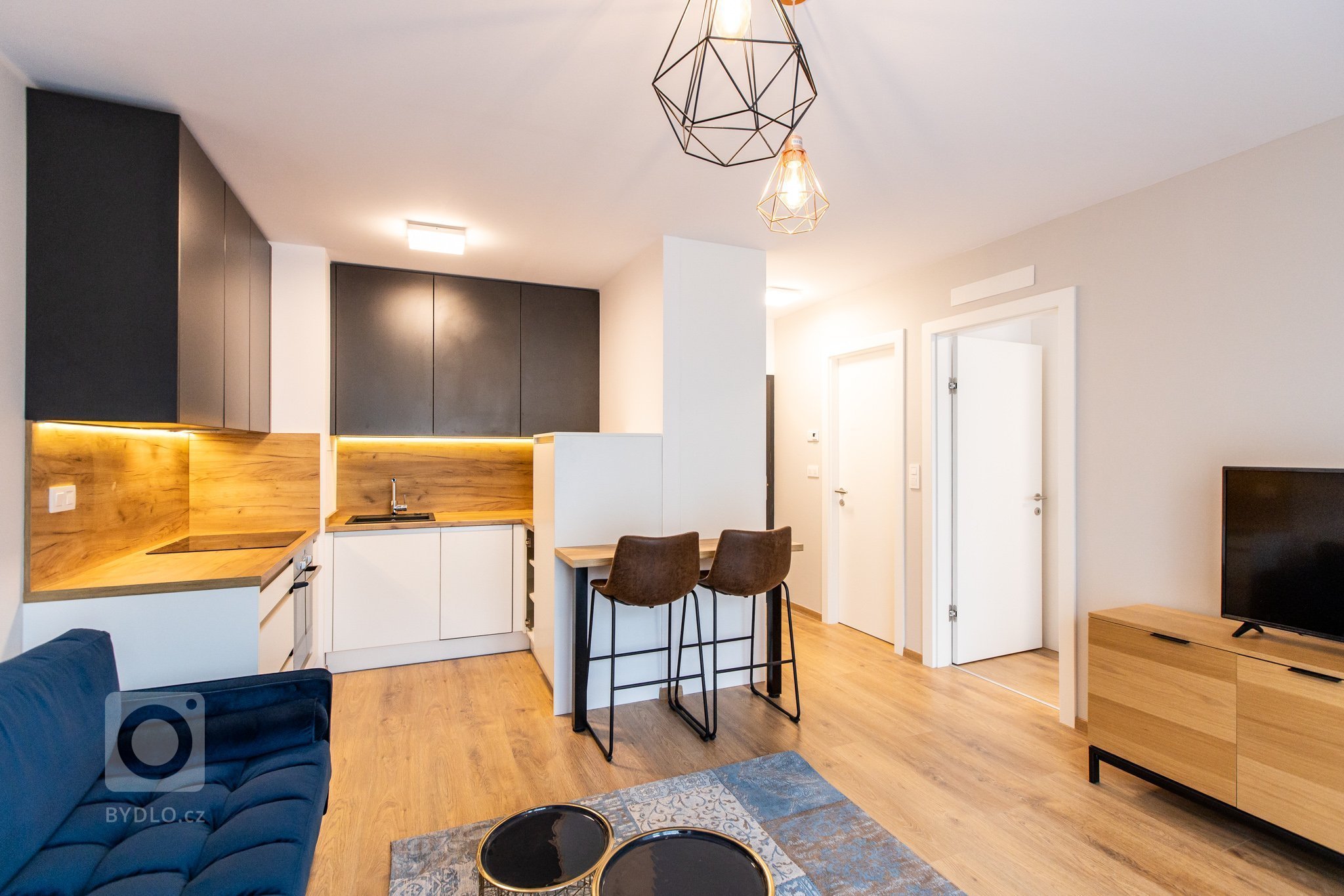 Krásne minimalisticky zariadený byt v Urban Residence, ktorého dominantou je modrá rohová sedačka. Kuchynská linka je krásne ladená v tónoch ceého bytu, aby…