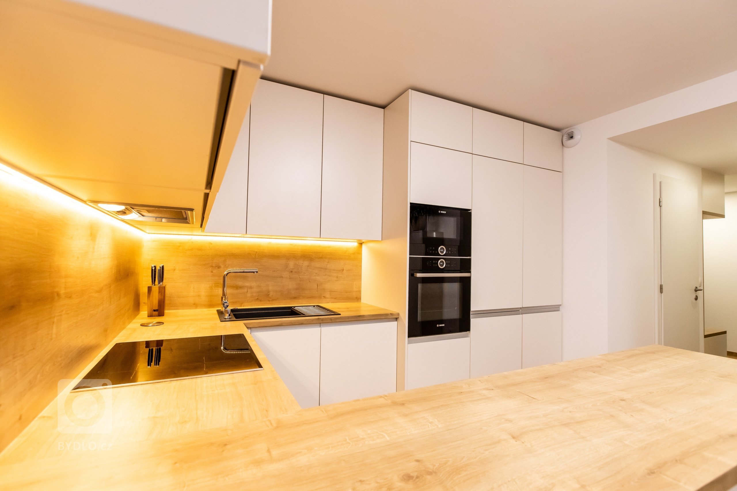 Materiály: Biely perleťový mat a Dub zlatý

Podsvietenie: Teplý&nbsp;LED pás

Madlá: Kuchyňa - Zafrézované hliníkové

Skrine - Madlo v tvare &quot;L&quot…