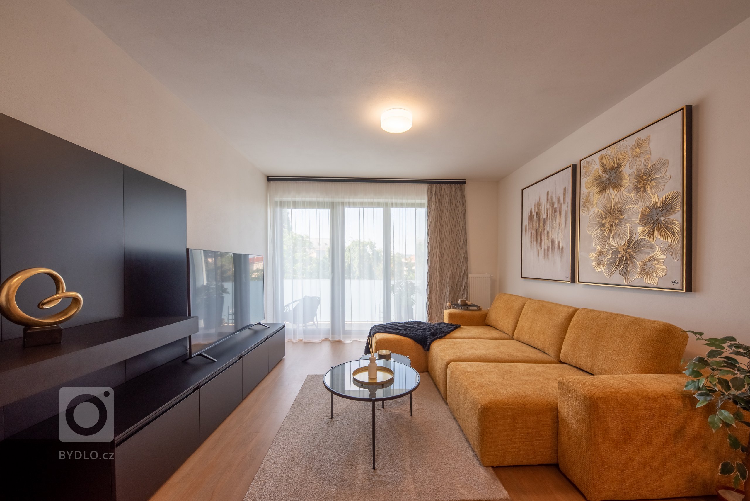 Realizace moderního obývacího pokoje a ložnice v glamour stylu.&nbsp;

Sedací souprava je z kolekce MONO s výsuvnými sedáky, obývací stěna je v černém matném…