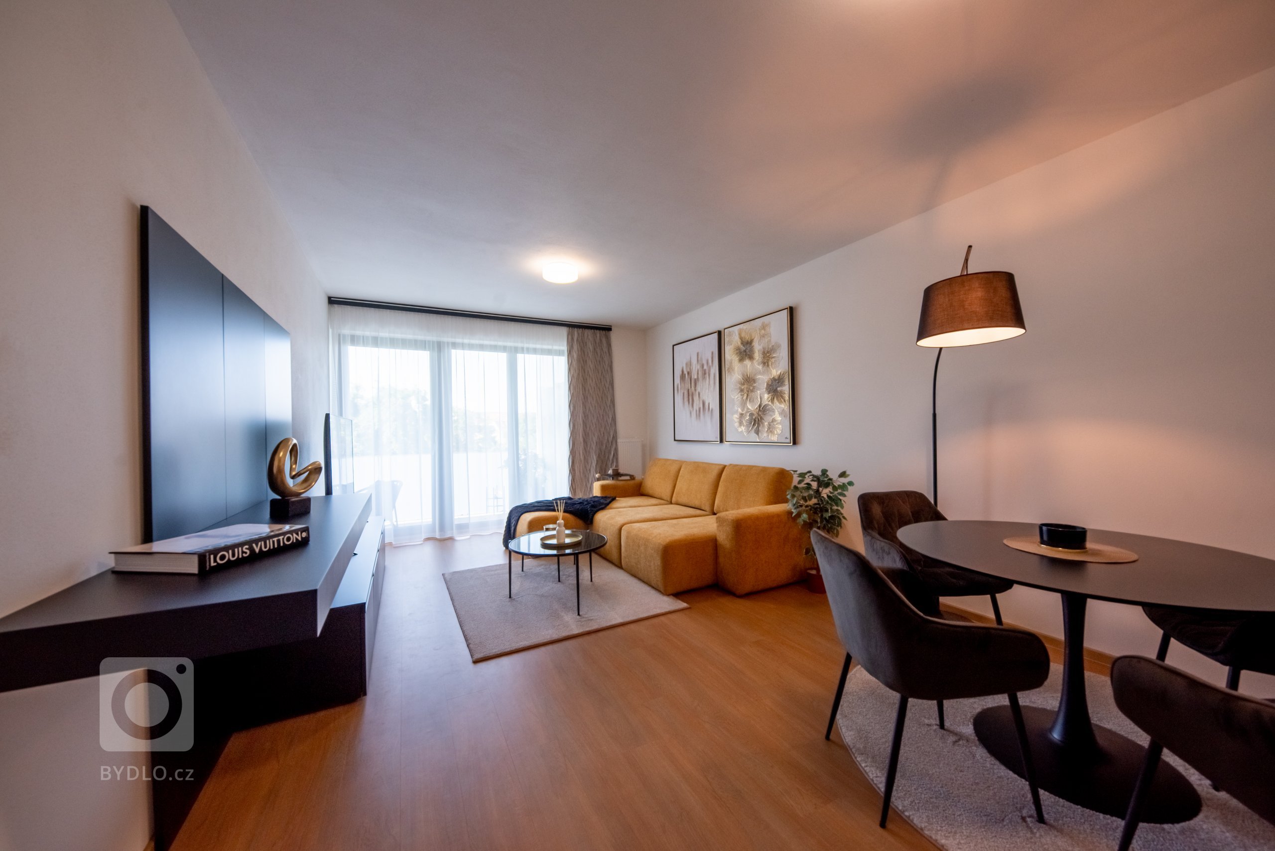 Realizace moderního obývacího pokoje a ložnice v glamour stylu.&nbsp;

Sedací souprava je z kolekce MONO s výsuvnými sedáky, obývací stěna je v černém matném…