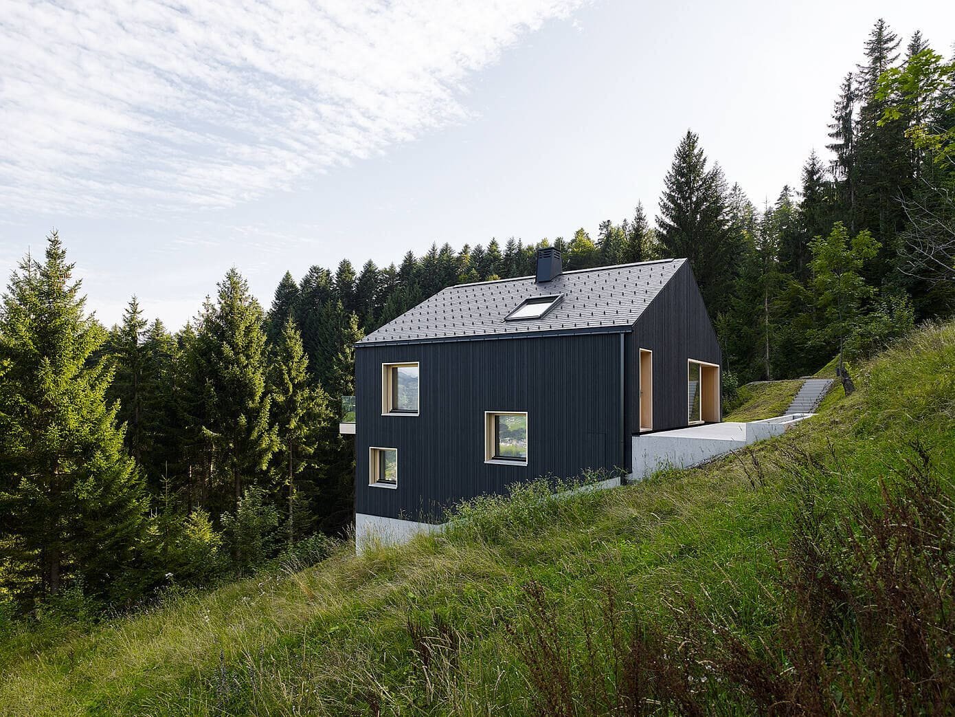 Černě oděný víkendový dům u lesa