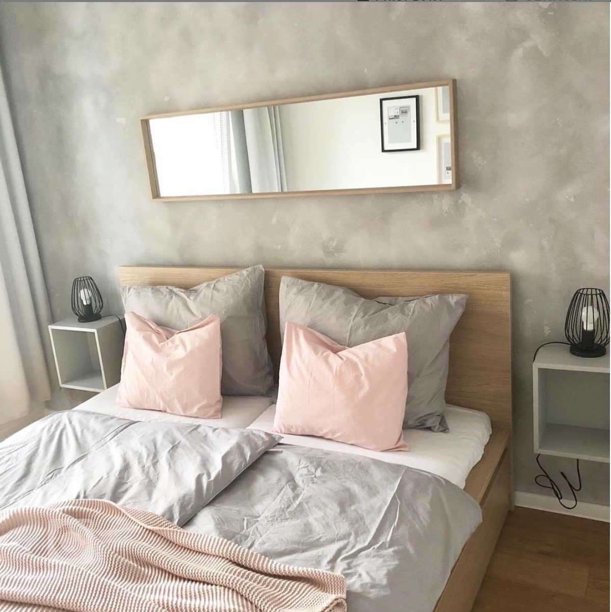 Betonová stěrka KABE Farben na stěně v ložnici v kombinaci s dřevěnými a kovovými prvky.