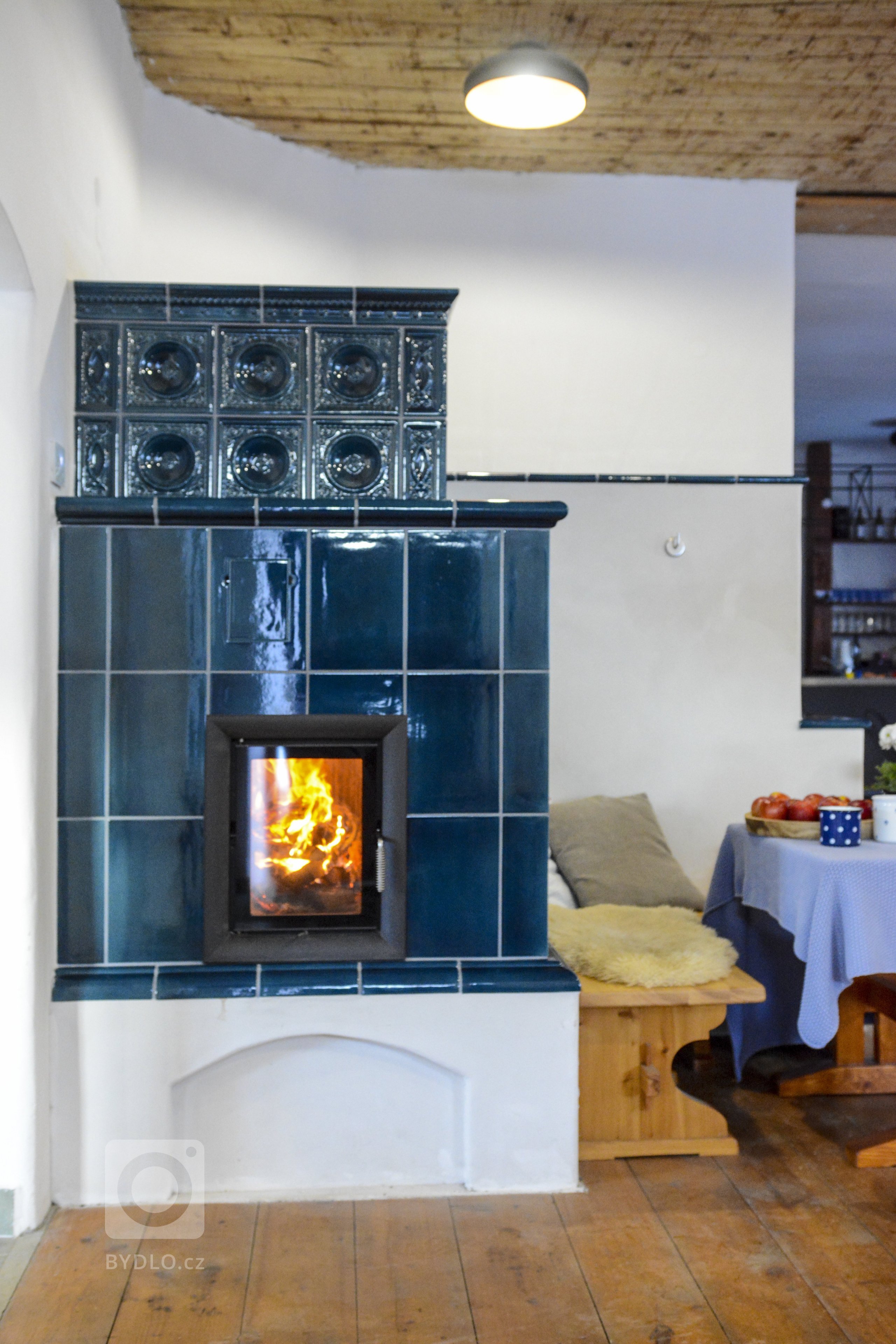 Realizace Romana Hanuše. Kachlová kamna s píckou poháněná vložkou Brunner HKD 4.1. Použity byly kachle hladké a Rustikal a&nbsp;římsa Flora, vše v tmavě modré…