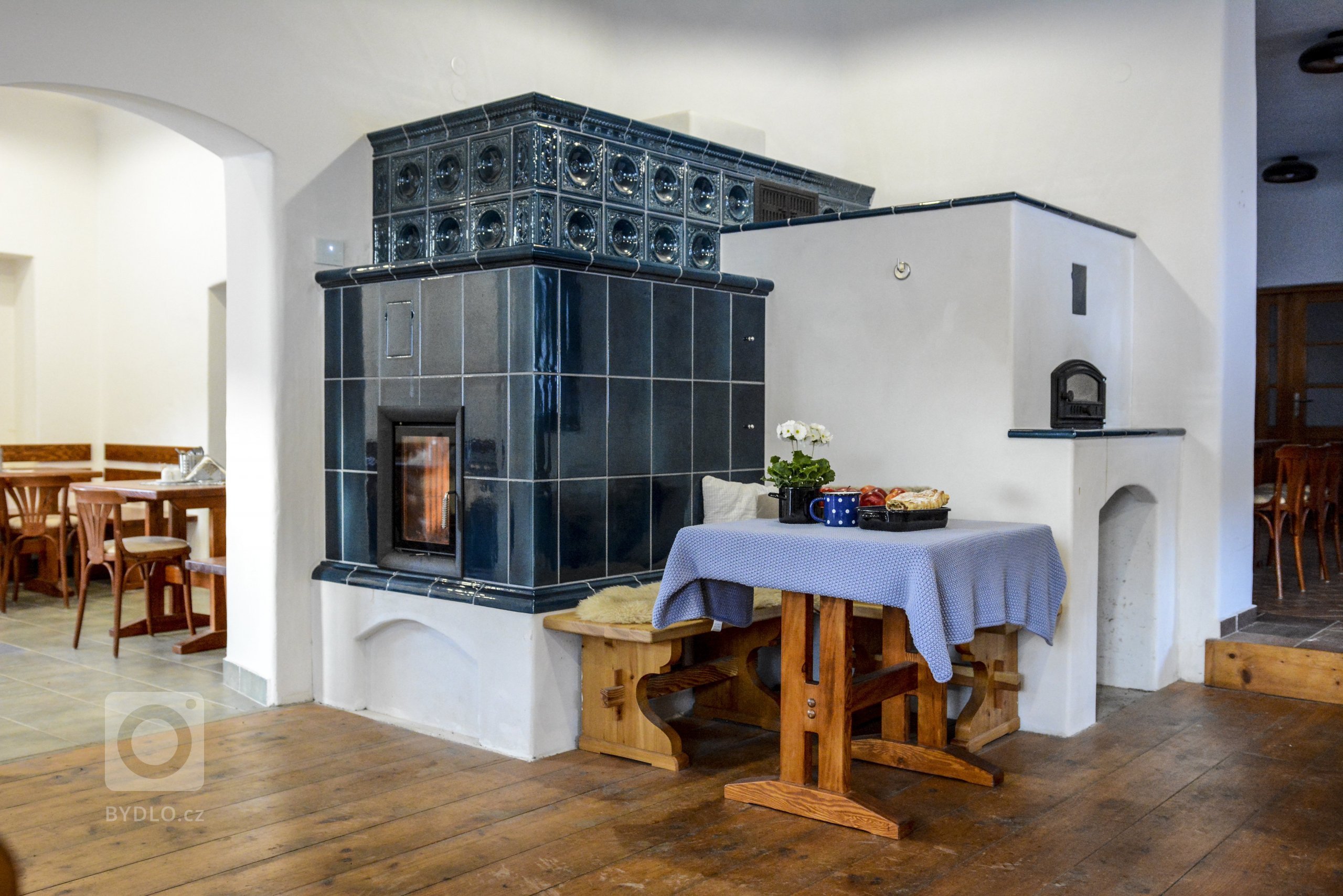 Realizace Romana Hanuše. Kachlová kamna s píckou poháněná vložkou Brunner HKD 4.1. Použity byly kachle hladké a Rustikal a&nbsp;římsa Flora, vše v tmavě modré…