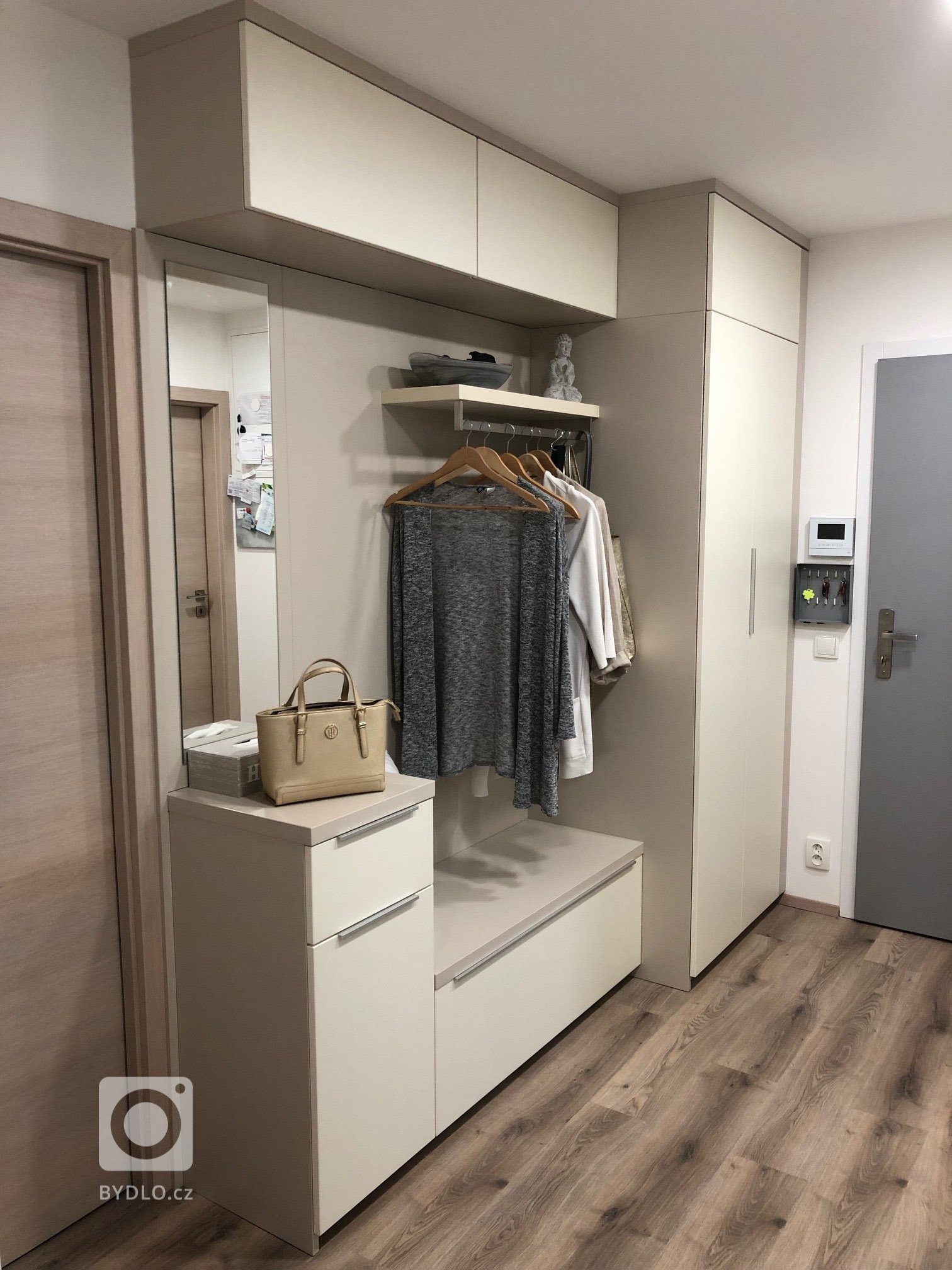 Vstupní chodba v moderních světlých tónech s výsuvnými policemi na boty ve velké botníkové skříni.