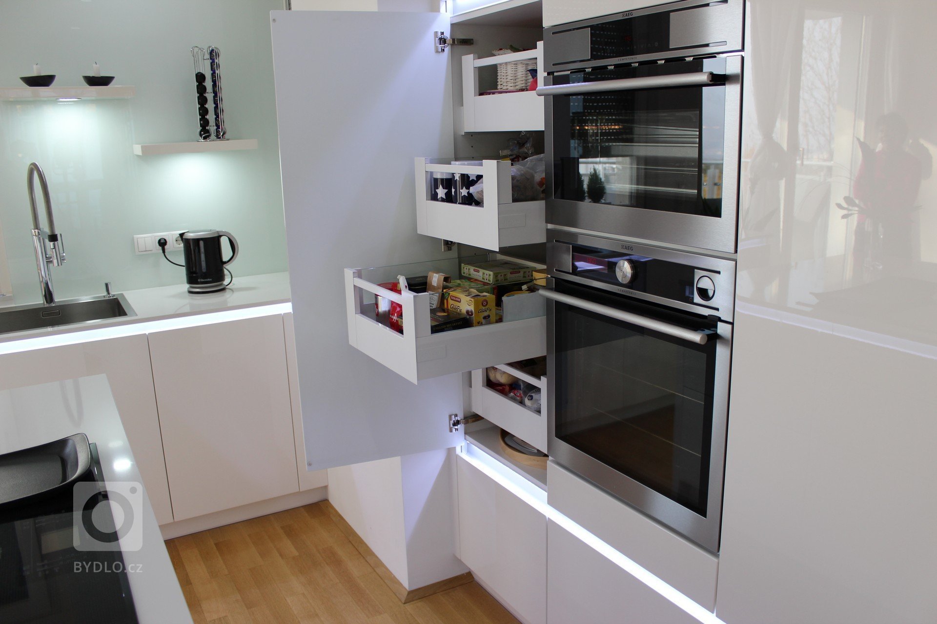 Realizace moderní kuchyně ve Vídni. Kuchyně INFINI - Dvířka lakovaná polyesterovým lakem ve vysokém lesku, výsuvy s el. otvíráním ServoDrive. Pracovní deska…