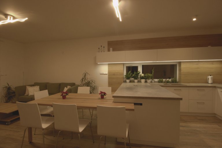 Vize klientky byla jasná, kuchyň s&nbsp;vysokým dřevěným obkladem a vybíhající horní bílá skříňka.

Kuchyně je ve tvaru U a na ní navazující stůl. Stůl je…