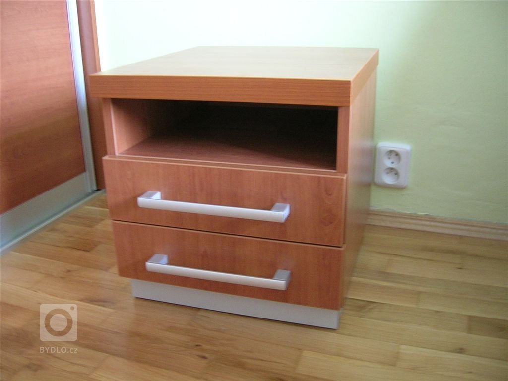 Ložnice s postelí s úložným prostorem, nočními stolky a vestavěnou skříní.
