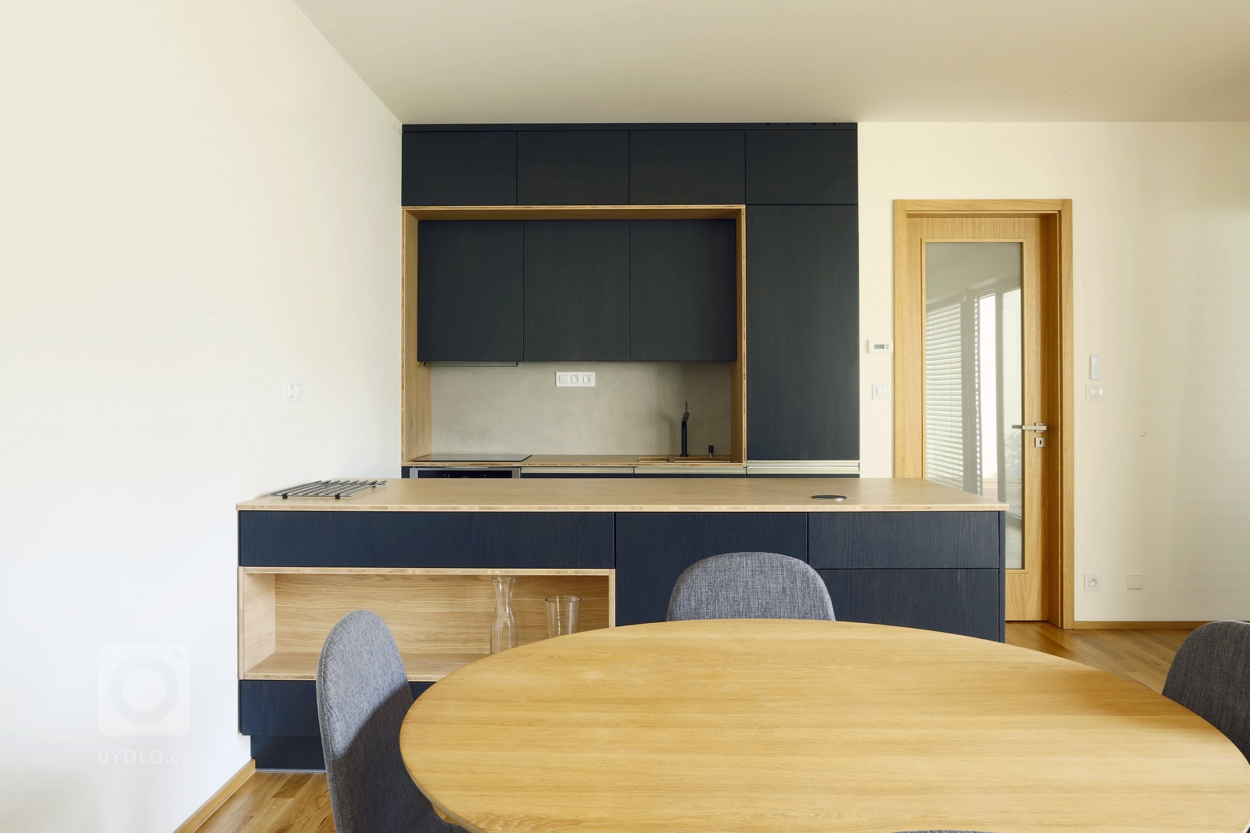 Odvážná kuchyně v novostavbě, kdy je tmavá barva zjemněná dubovou bio deskou a kresba dřeva pod dýhovaným mořeným dvířkem krásně prostupuje a vytváří zajímavý…