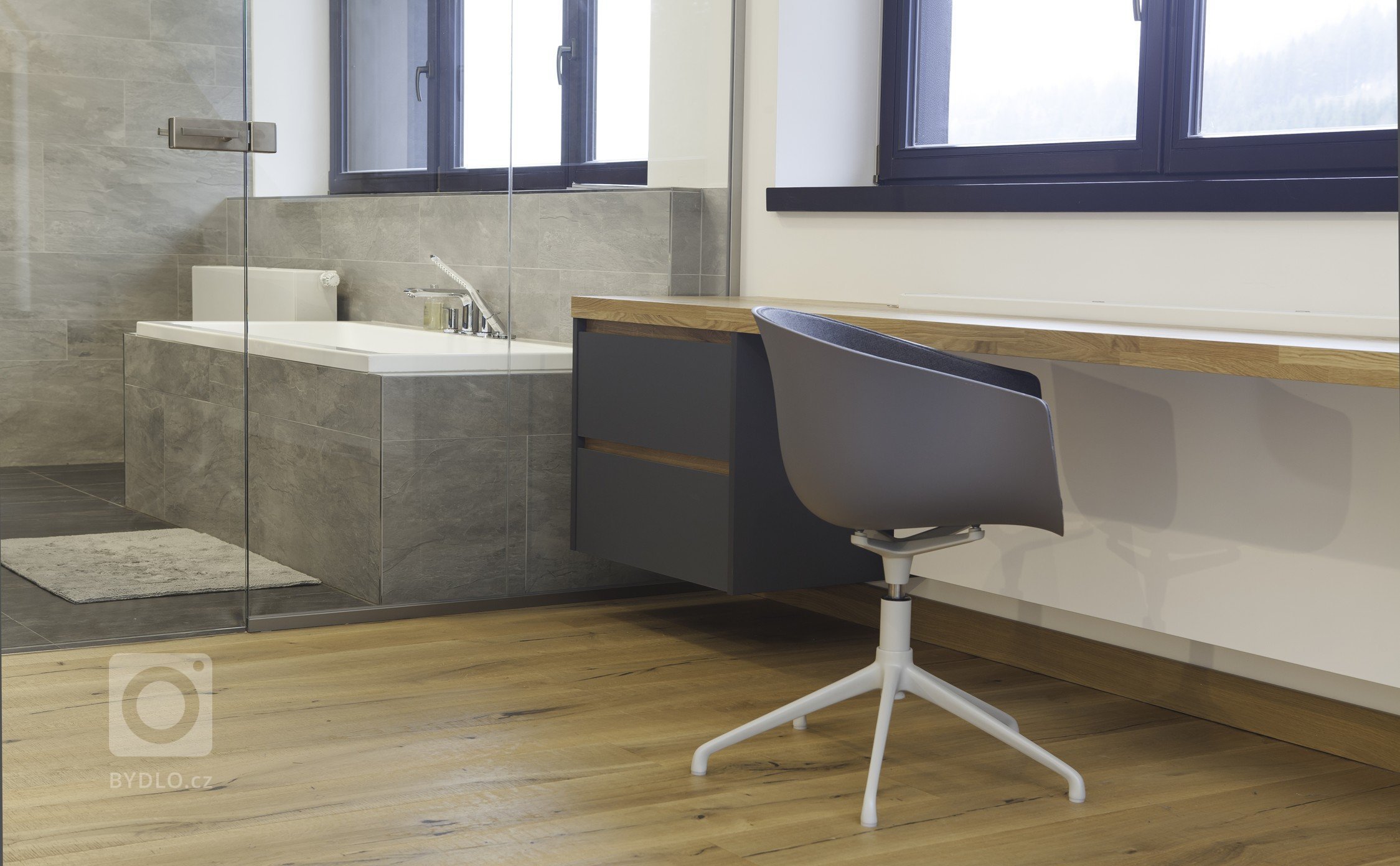 Ložnice rodičů a koupelna tvoří velkorysý prostor s minimem nábytku. Koupelna je od ložnice oddělená skleněnou stěnou.

V kuchyni matná šedá a černá příjemně…