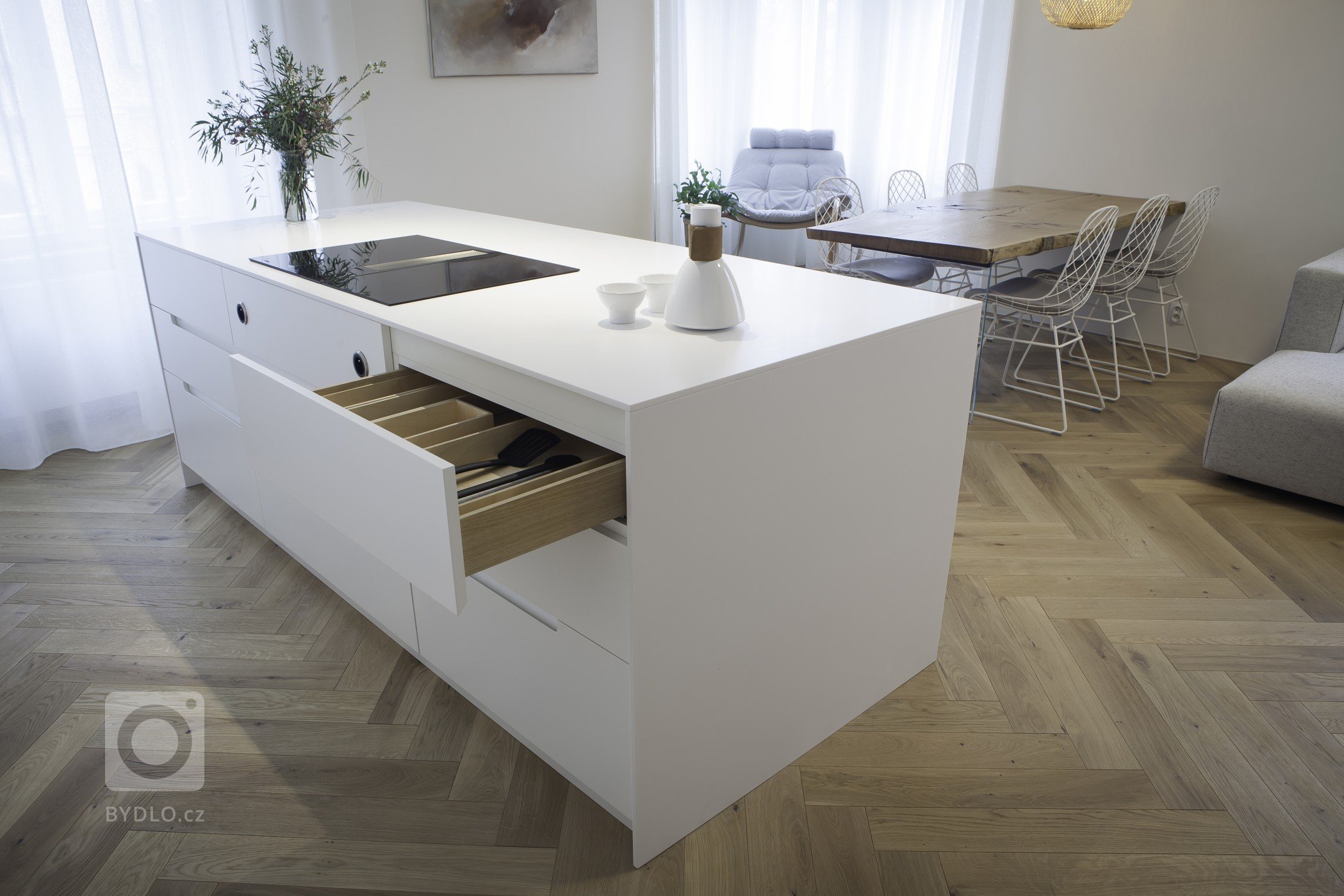 Kuchyňská linka s&nbsp;velkorysým ostrůvkem z materiálu Corian. Netradičním prvkem kuchyně je uzavíratelná část linky, díky které bude kuchyň vypadat uklizeně…