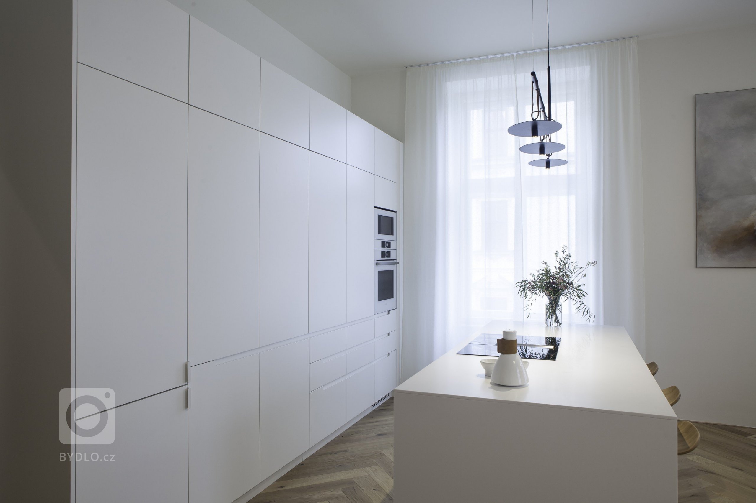 Kuchyňská linka s&nbsp;velkorysým ostrůvkem z materiálu Corian. Netradičním prvkem kuchyně je uzavíratelná část linky, díky které bude kuchyň vypadat uklizeně…