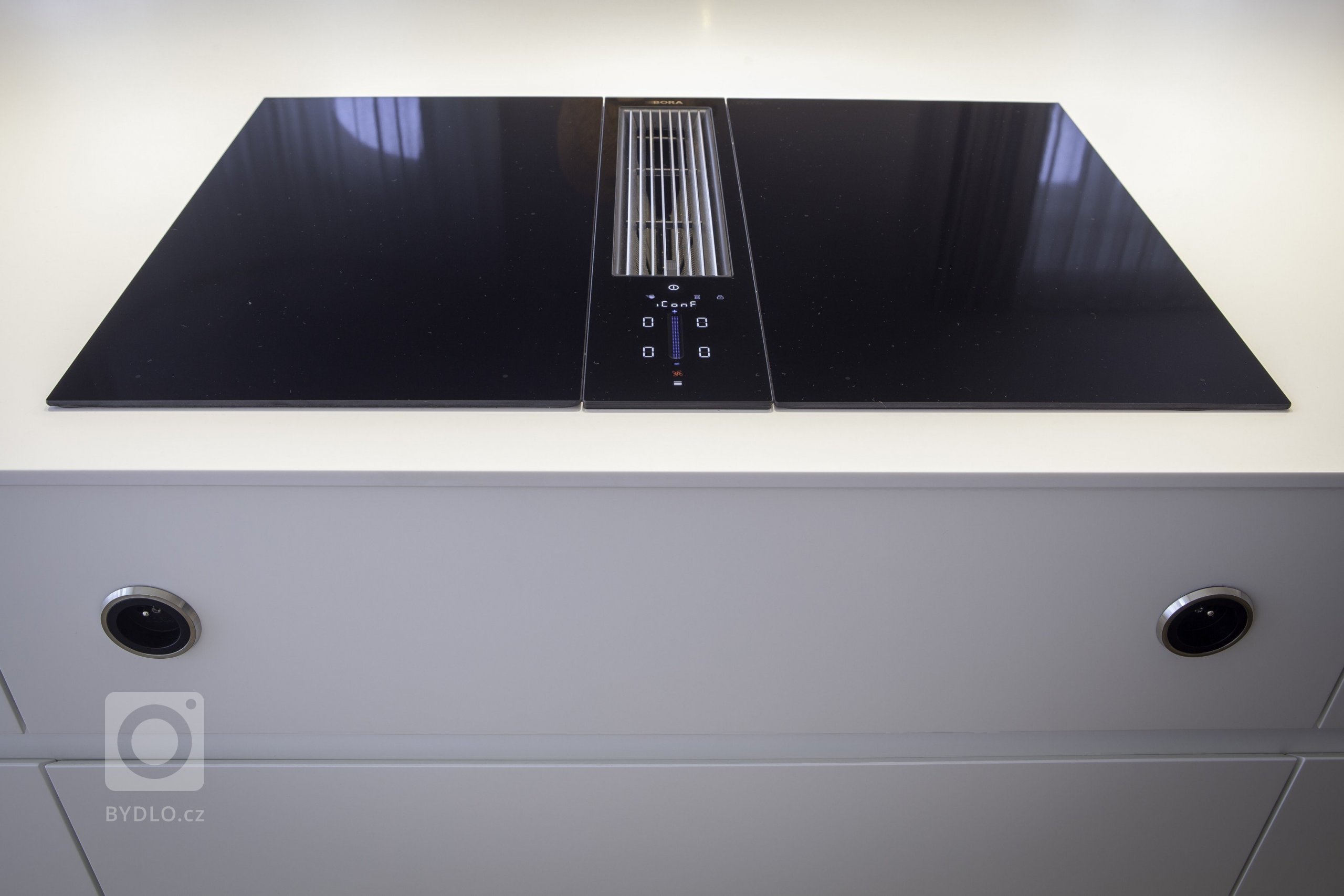 Kuchyňská linka s&nbsp;velkorysým ostrůvkem z materiálu Corian. Netradičním prvkem kuchyně je uzavíratelná část linky, díky které bude kuchyň vypadat uklizeně…