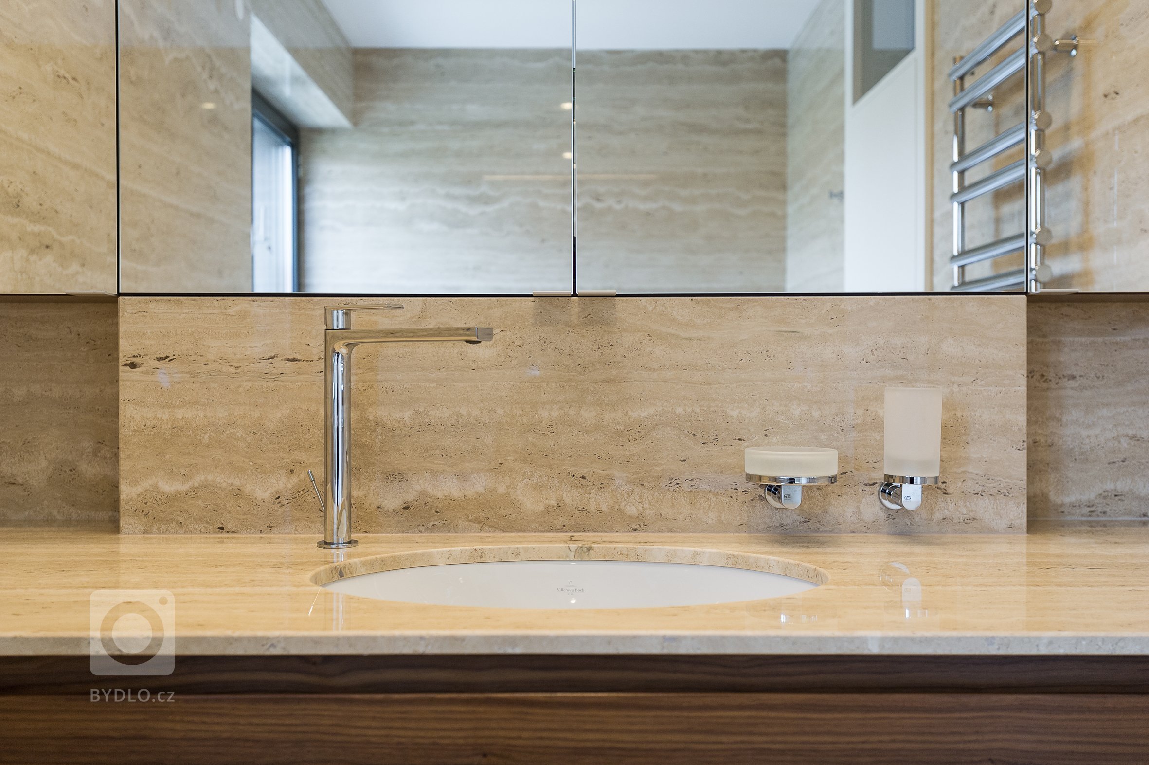 Koupelna obložena velkoformátovými travertinovými obklady.