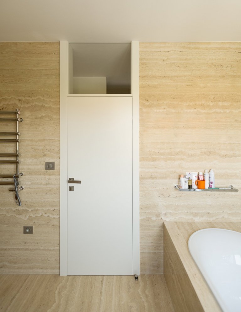 Koupelna obložena velkoformátovými travertinovými obklady.