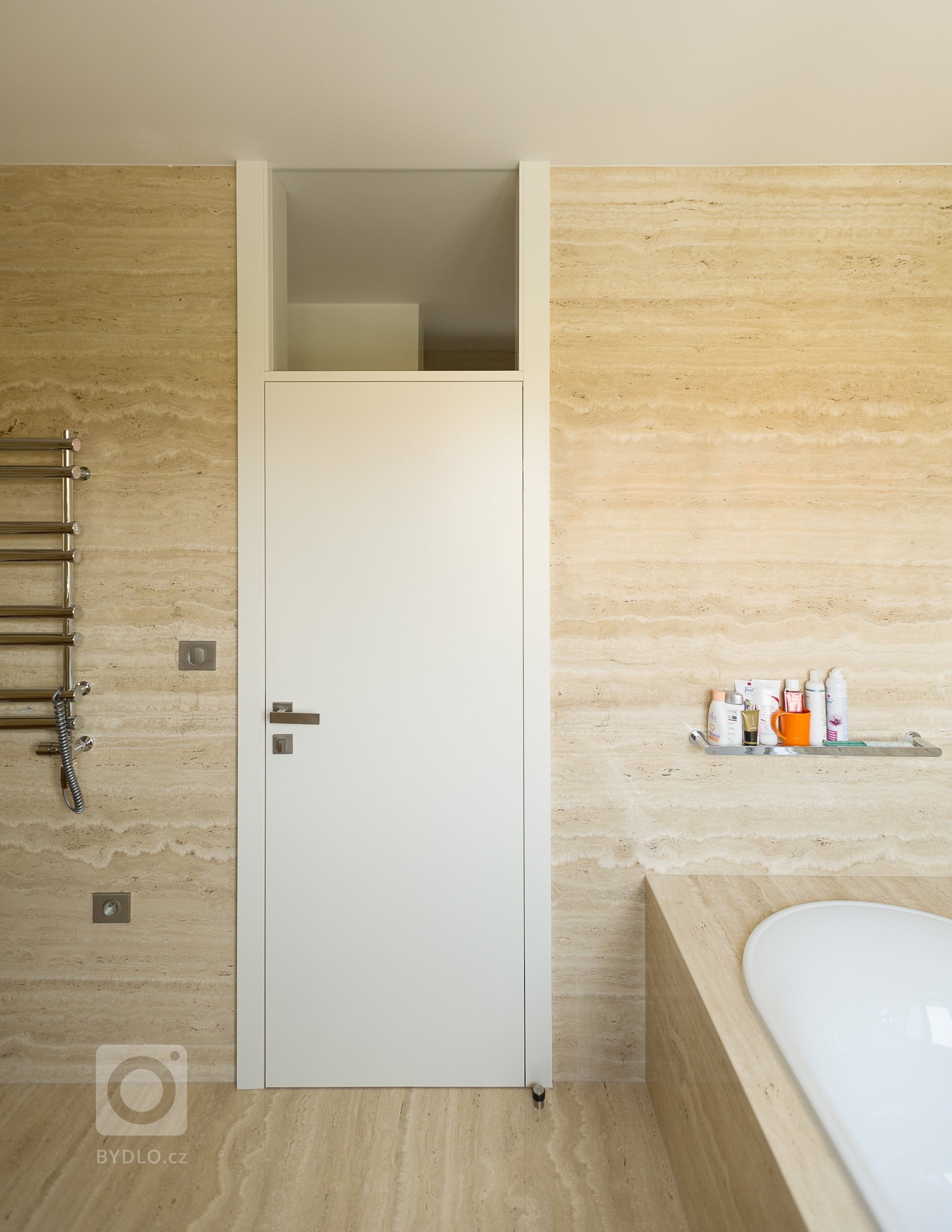 Koupelna obložena velkoformátovými travertinovými obklady.