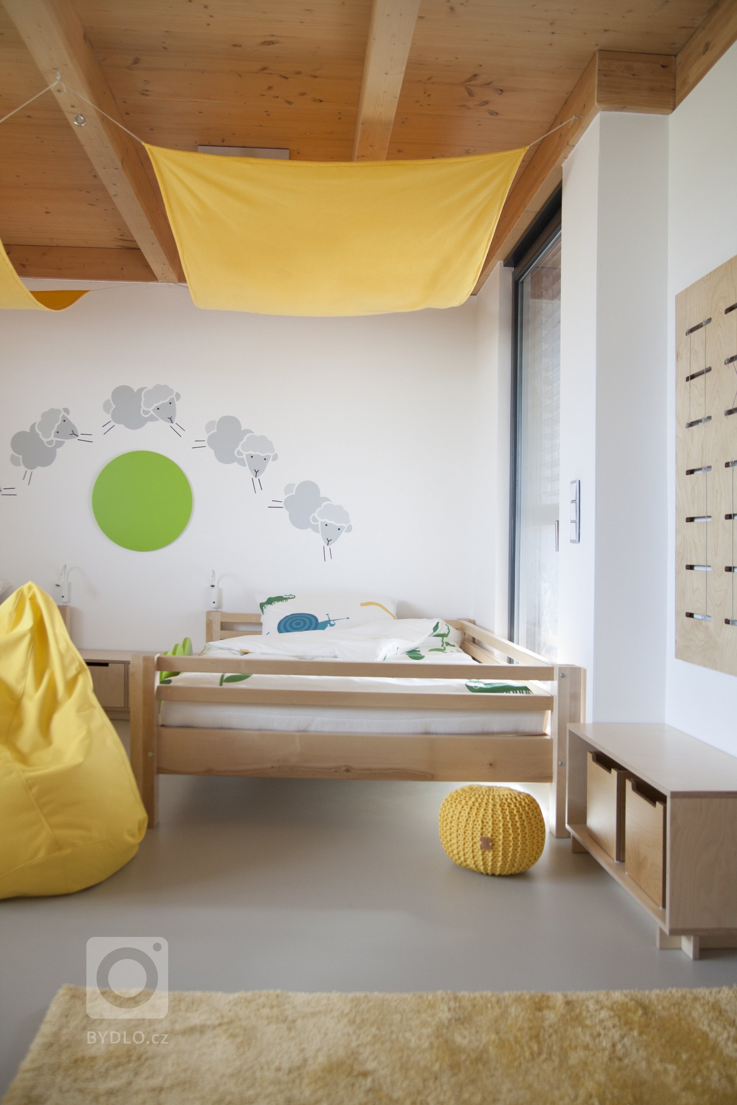 Dětská postel - kdo by nechtěl postel s baldachýnem? A kdo by nechtěl velikánskou postel, na kterou se vejde celá rodina, děti i rodiče? Na zeď jsme namalovali ovečky, peřiny jsme povlékli do zvířátkového povlečení, aby dítka po náročném dni zaručeně rychle usnuly. 