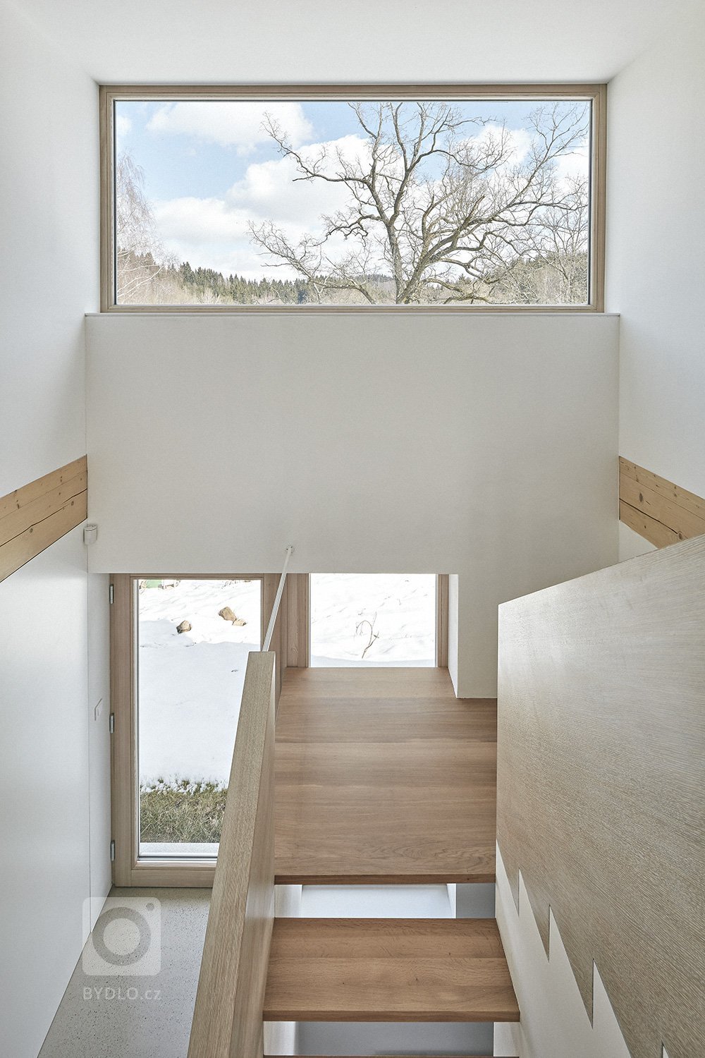 Pozemek leží na hraně svahu v&nbsp;centru malé obce na Vysočině. Na půdorysné stopě bývalého statku vznikl dům a stodola. Dům má podél jihozápadní fasády kryté…