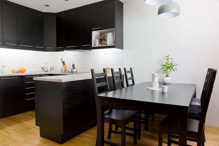 Kuchyně v černé barvě s dekorem dřeva ladí s jídelním koutem 