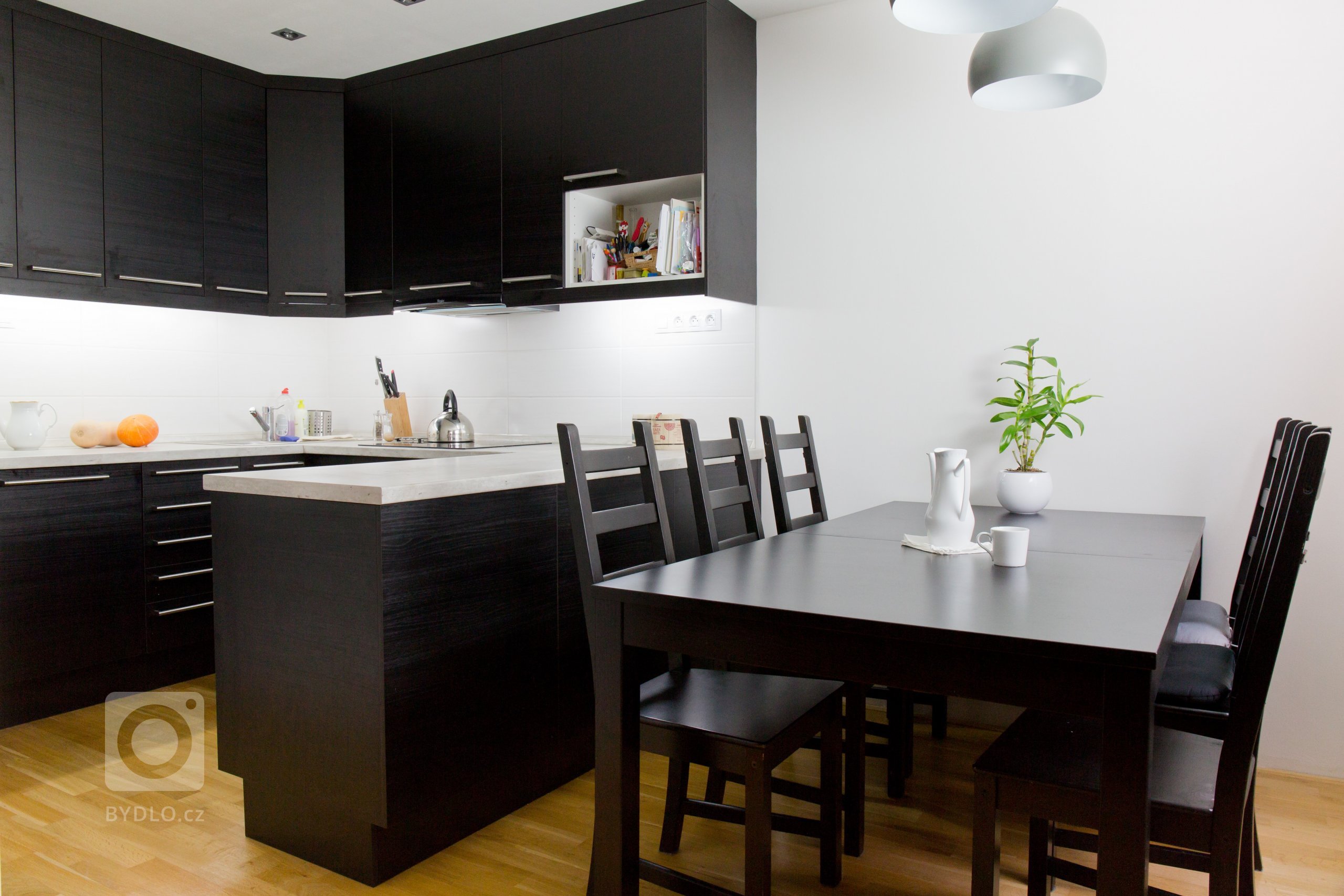Kuchyně v černé barvě s dekorem dřeva ladí s jídelním koutem 