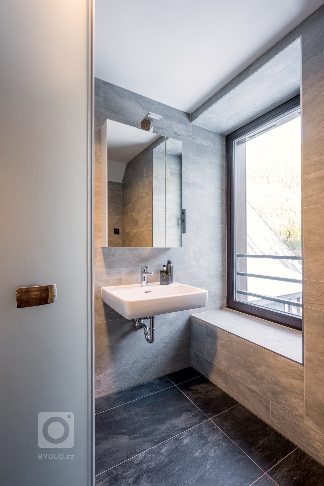 Koncept interiéru je laděn do přírodních materiálů a tmavších barev v&nbsp;kombinaci s&nbsp;bronzem, alcantarou a koňakovou kůží. Podlaha je až na koupelny…