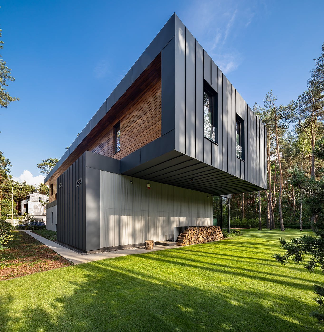 Dům s betonovou fasádou obklopený lesy