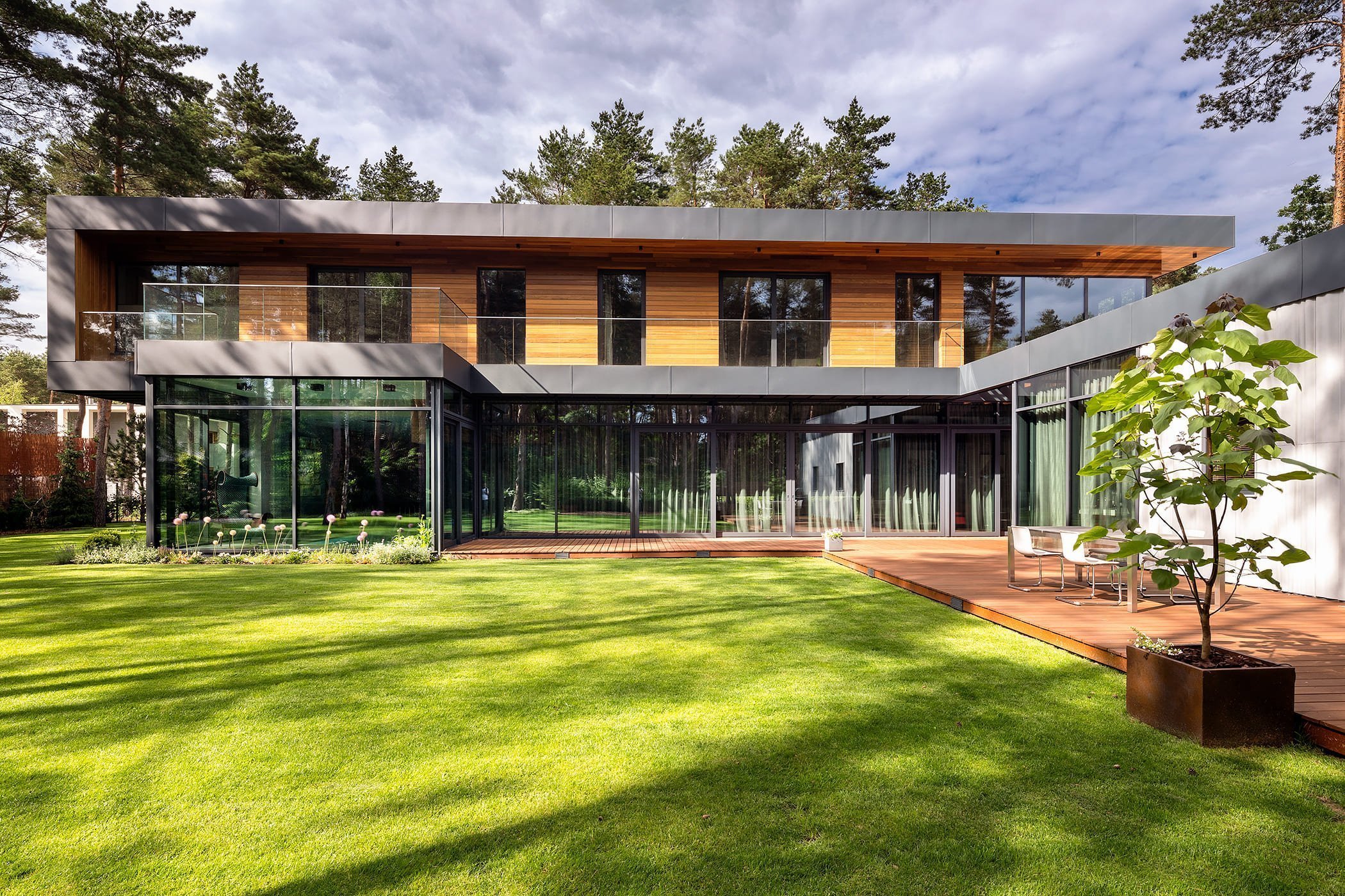 Dům s betonovou fasádou obklopený lesy