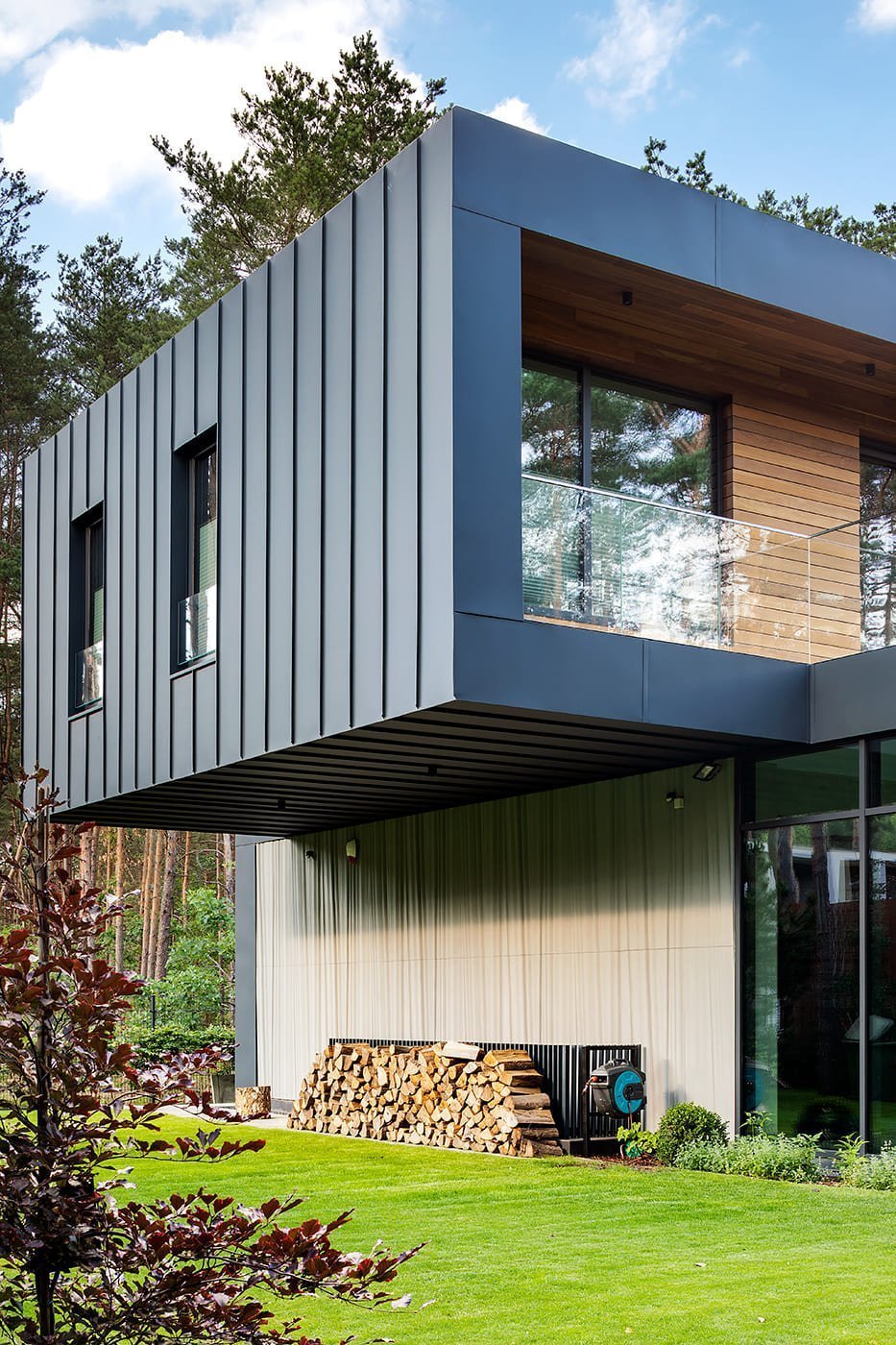 Dům s betonovou fasádou obklopený lesy