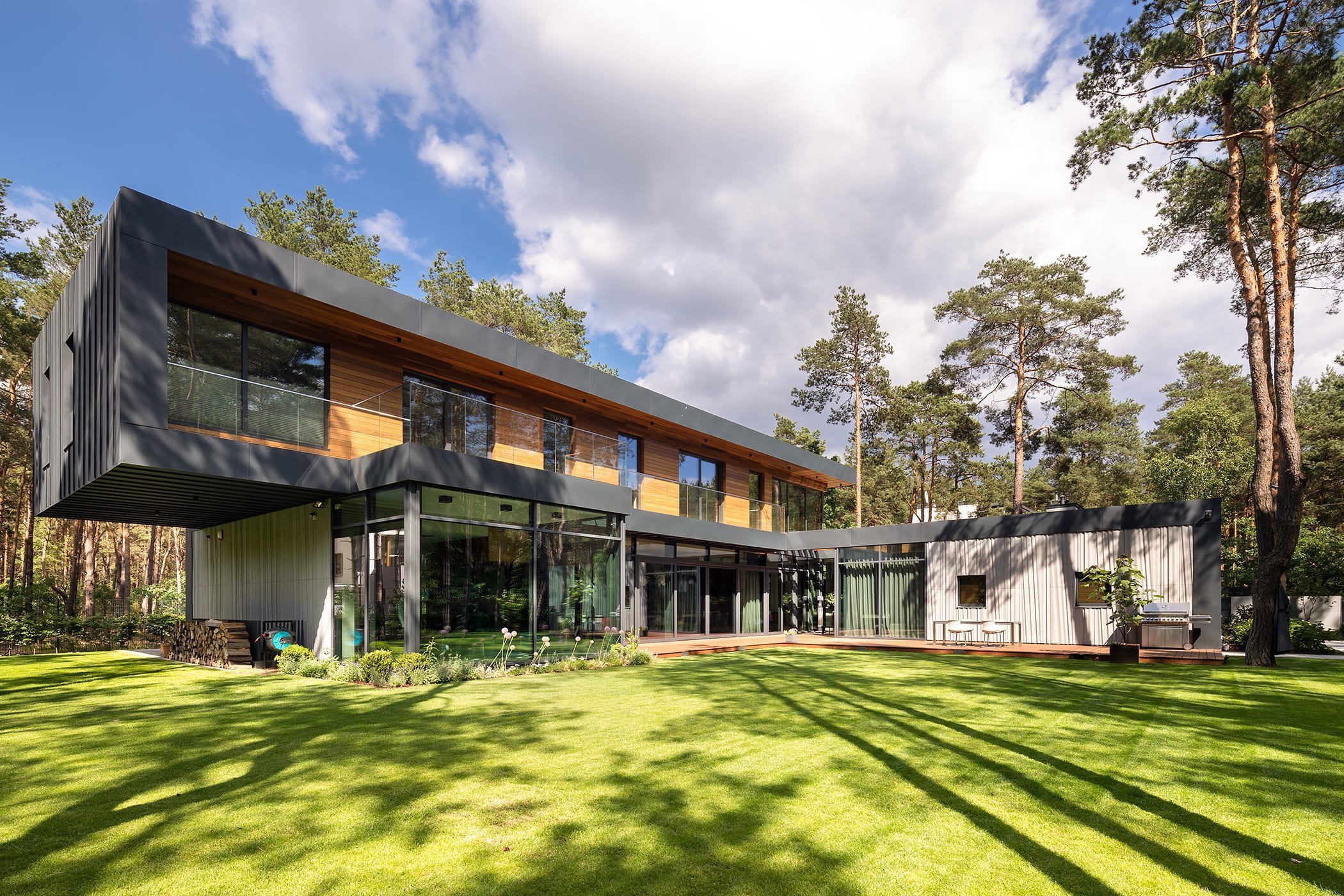 Dům s betonovou fasádou obklopený lesy