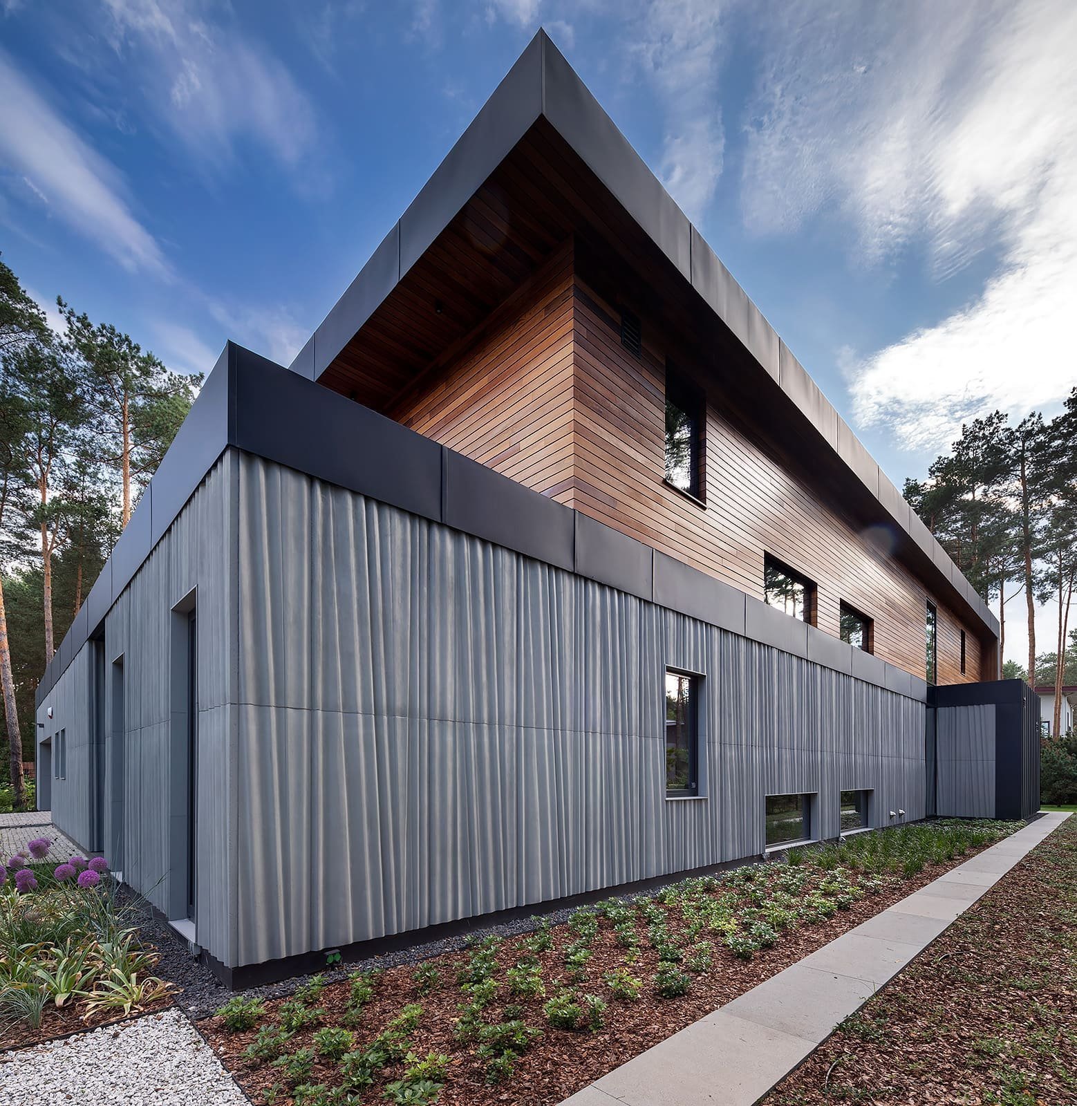 Dům s betonovou fasádou obklopený lesy