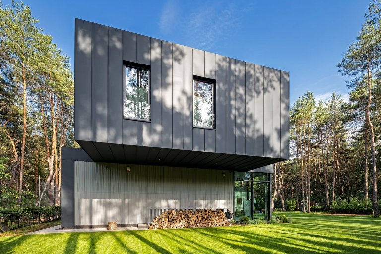 Dům s betonovou fasádou obklopený lesy