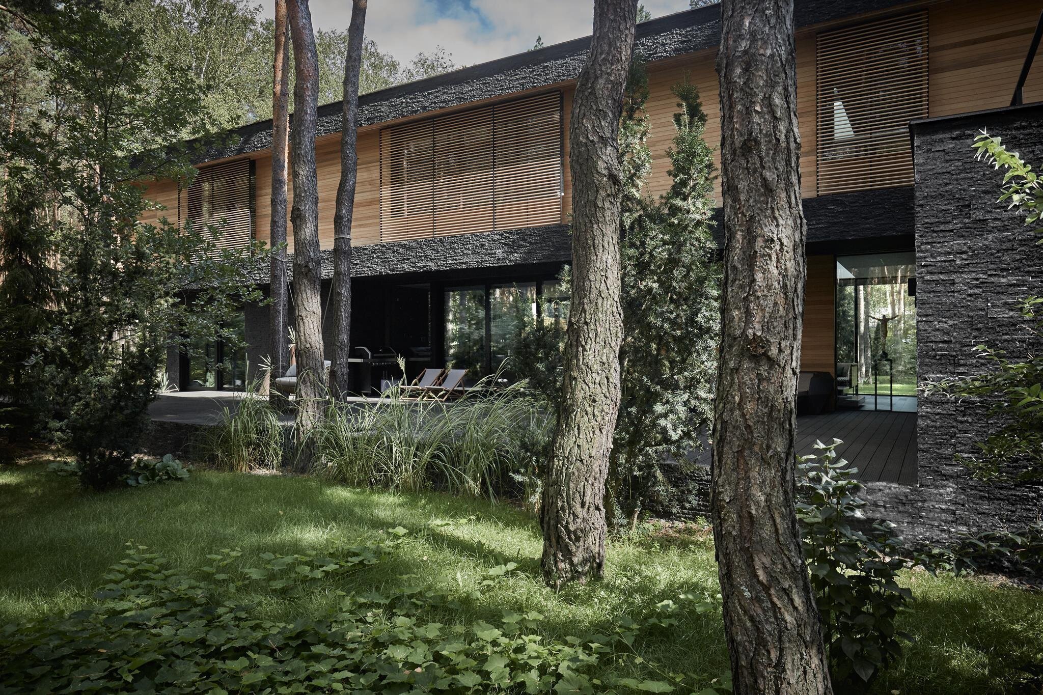 Dům s fasádou z břidlice uprostřed lesa