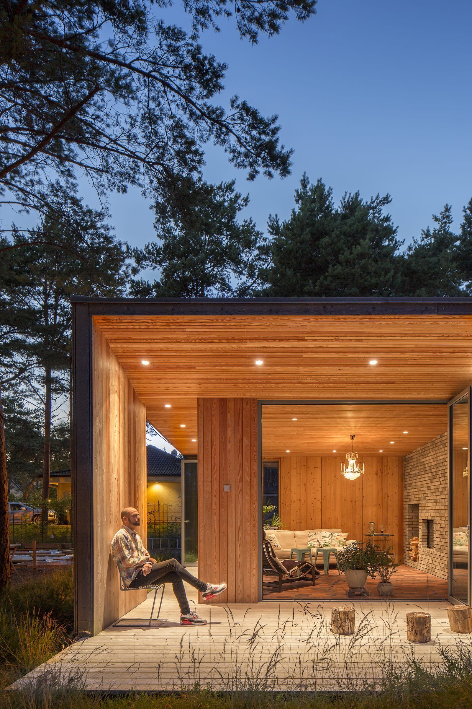 Přízemní dřevostavba mezi borovicemi a domem pro babičku